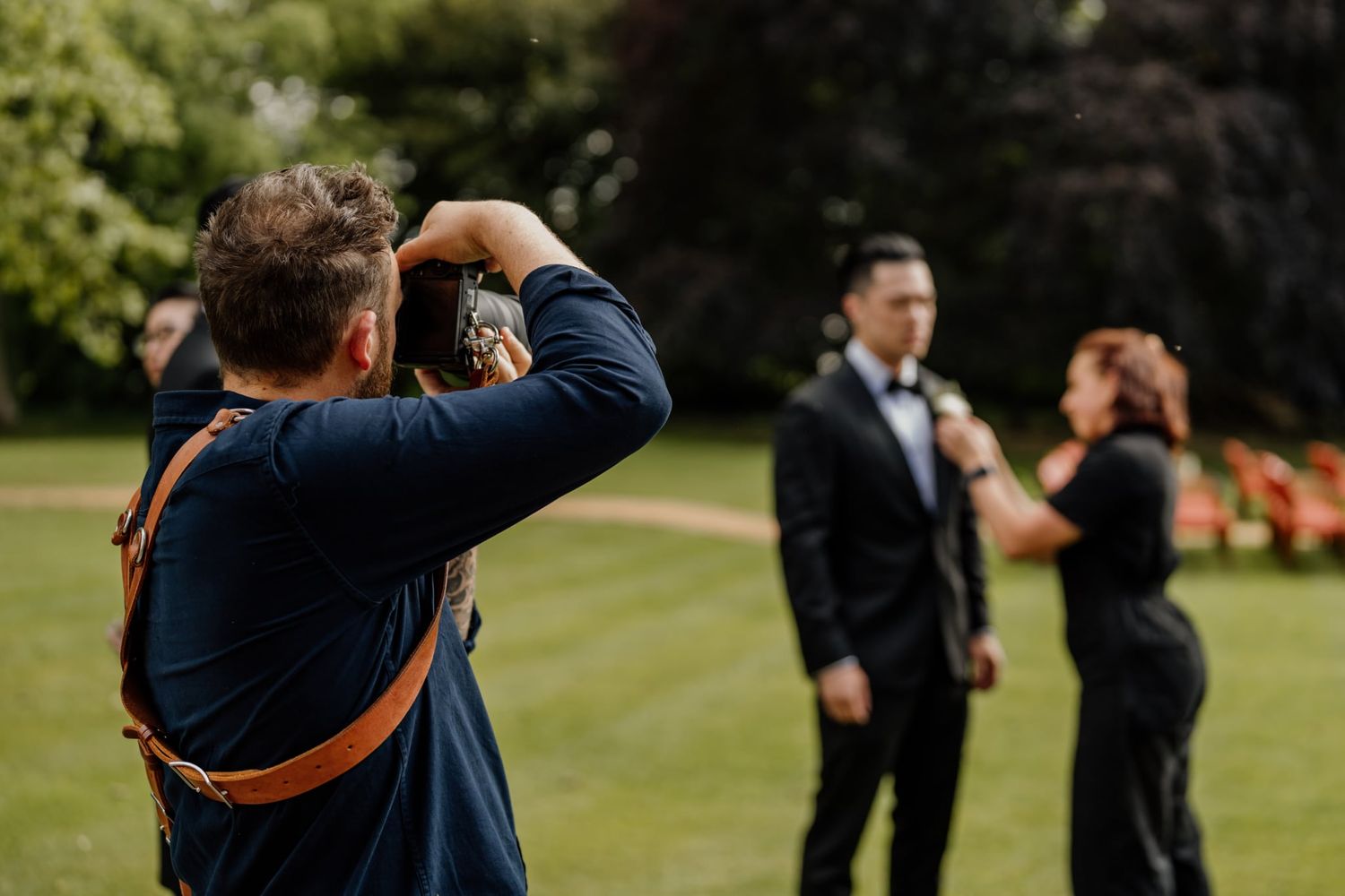 Wedding photographers with professional cameras capturing moments at an outdoor ceremony.