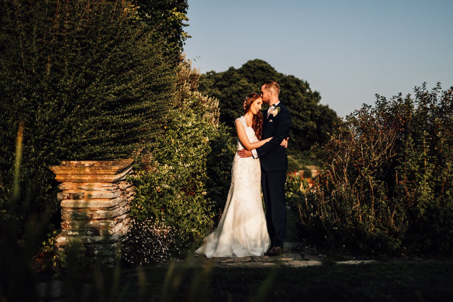 Wedding couple photographed in natural outdoor setting during sunset.