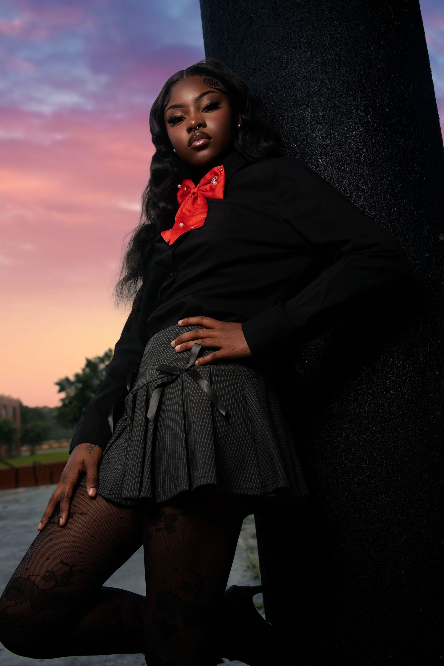 Artistic fashion portrait series in black dress and tights against dramatic sunset sky backdrop.