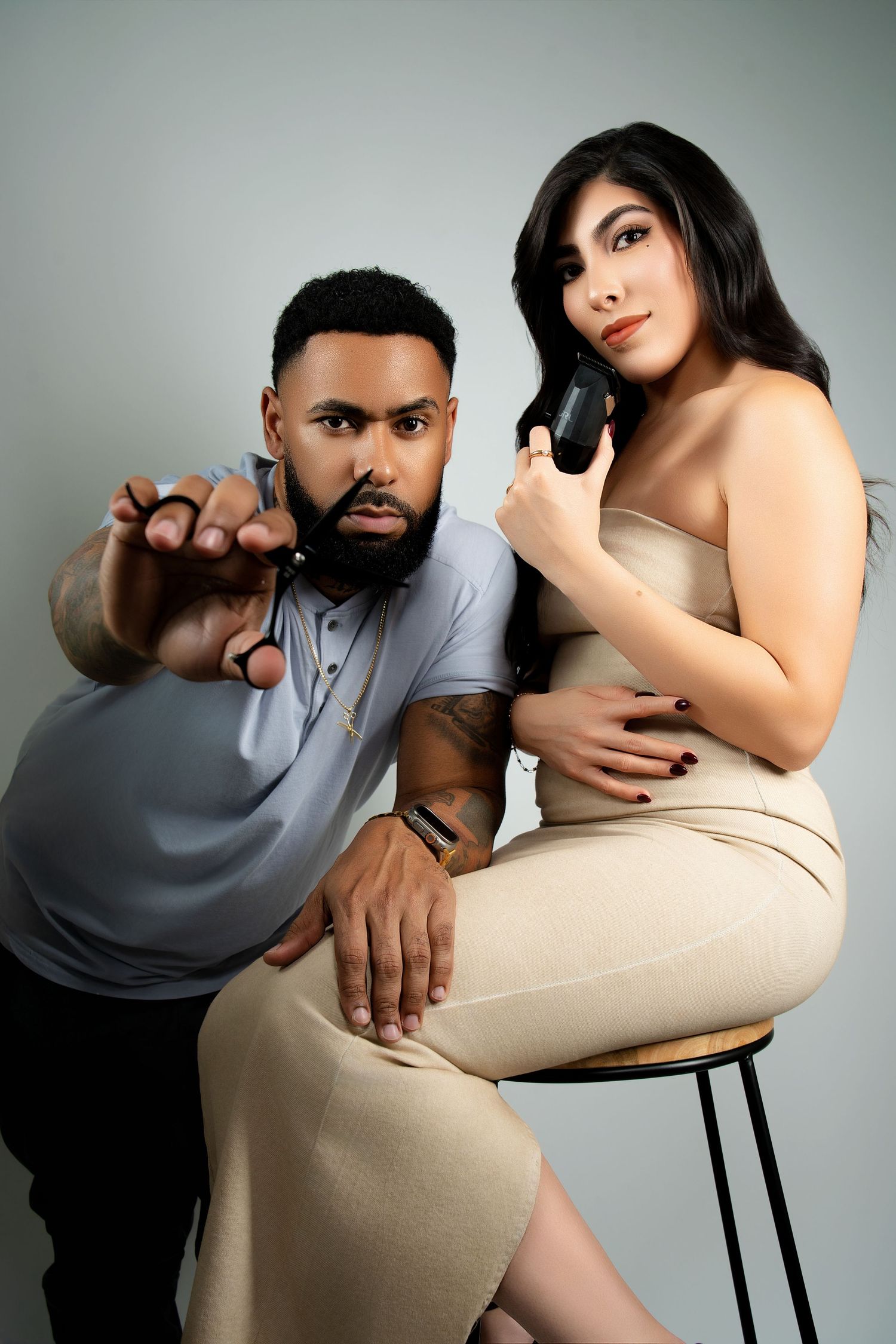 Fashion portrait of a couple in neutral tones posing dramatically in studio lighting.