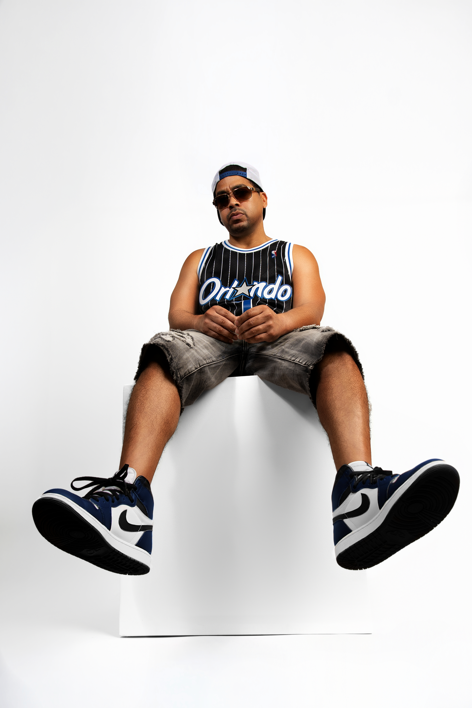 A person in an Orlando basketball jersey and sunglasses sits in multiple artistic poses against a white background.