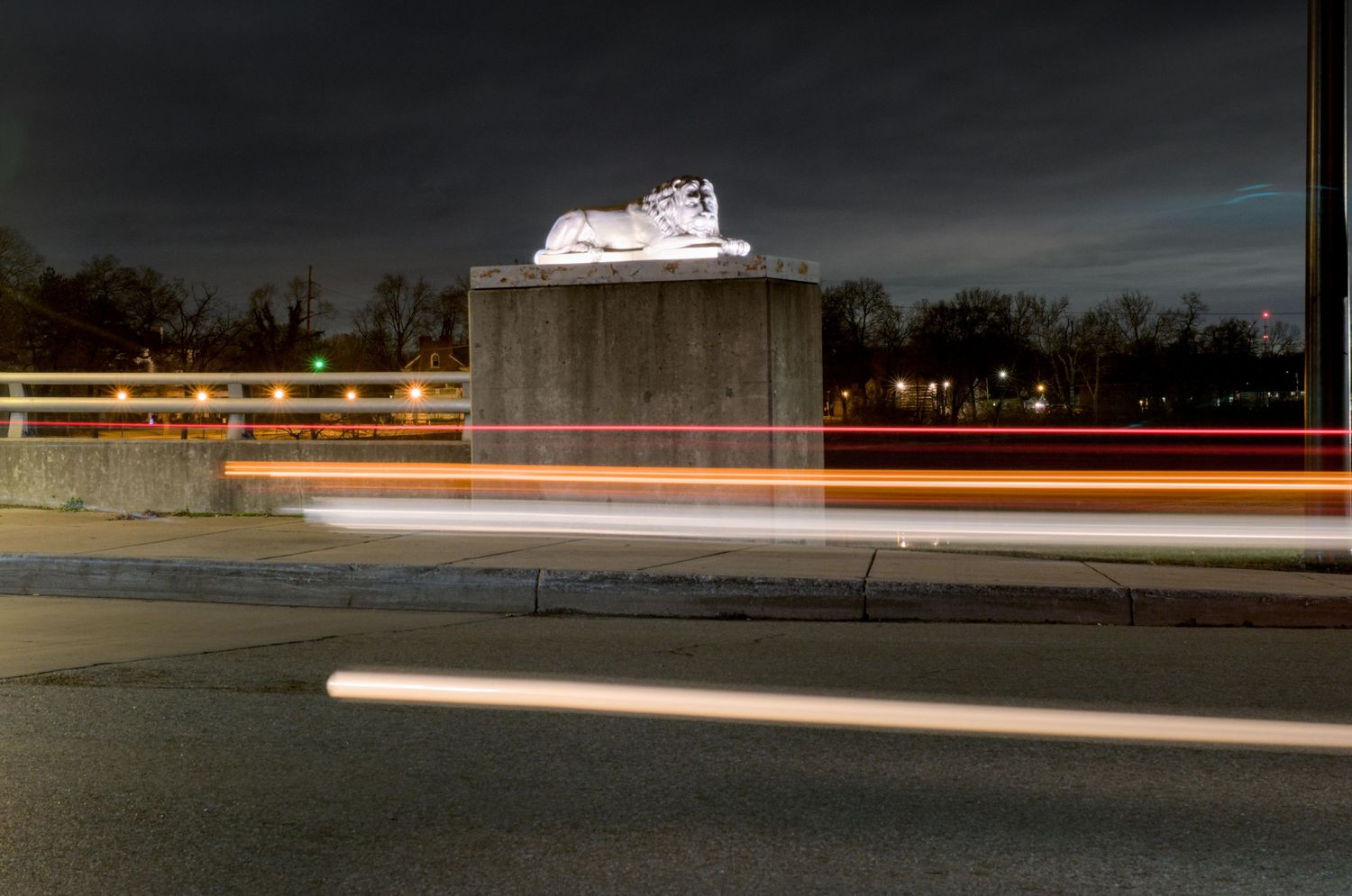 White and red streaks are blurred horizontally across the night photo with a majestic statue of a lion in the background in Franklin, Ohio.