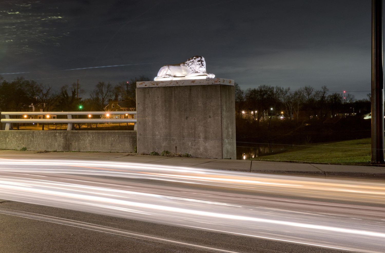 White and red streaks are blurred horizontally across the night photo with a majestic statue of a lion in the background in Franklin, Ohio.