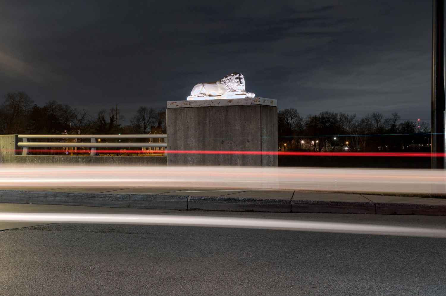 White and red streaks are blurred horizontally across the night photo with a majestic statue of a lion in the background in Franklin, Ohio.