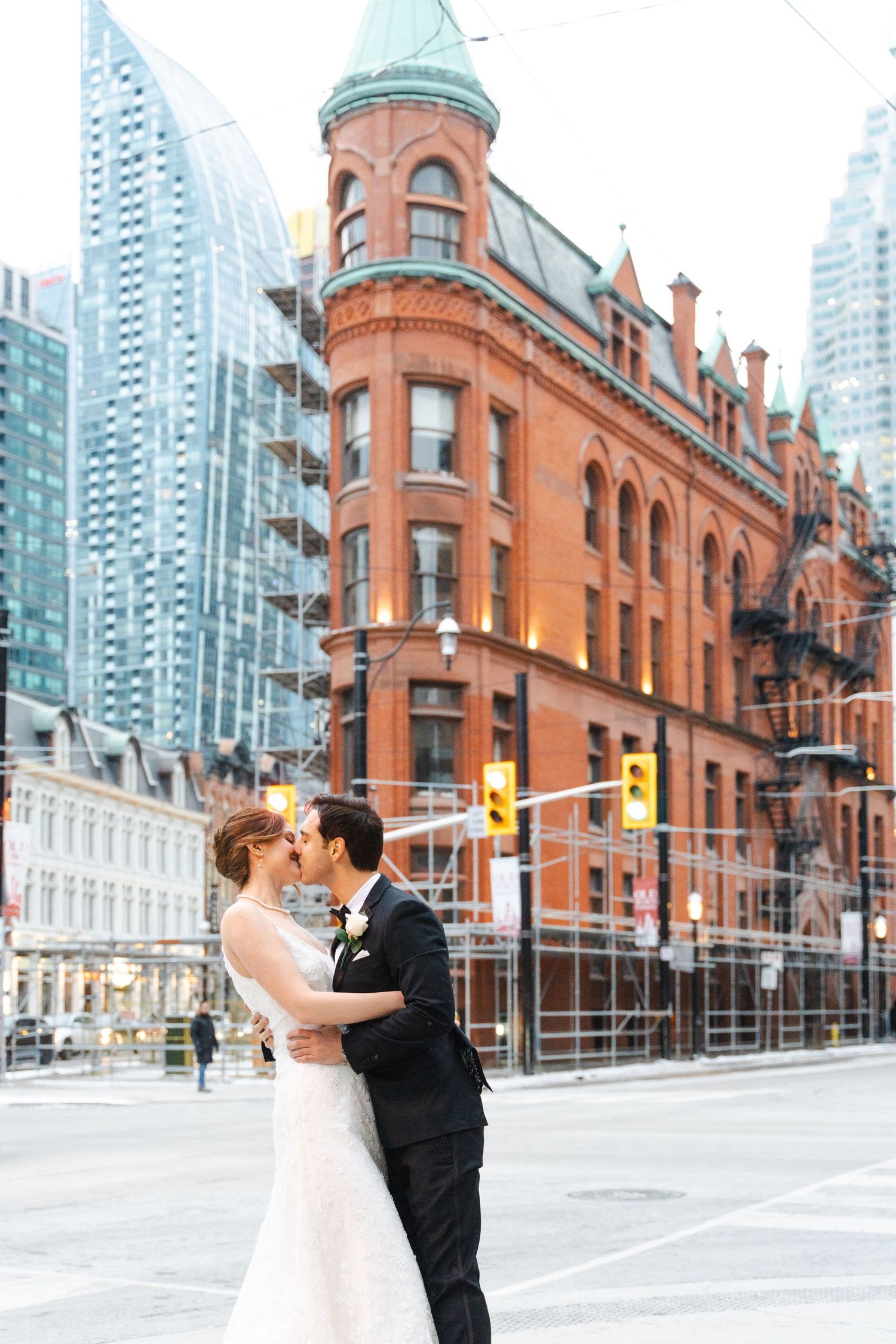 Bride and groom embracing in front of Toronto’s iconic Gooderham Building, also known as the Flatiron Building, in the historic St. Lawrence