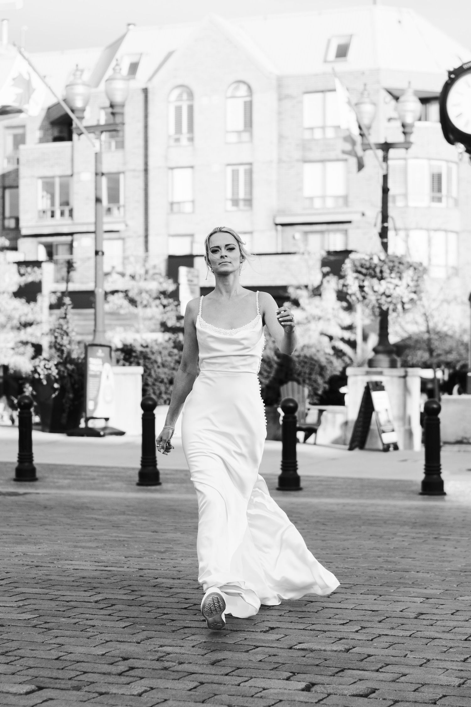 Black-and-white street portrait of a bride walking in her flowing wedding dress through Downtown Etobicoke, Toronto.