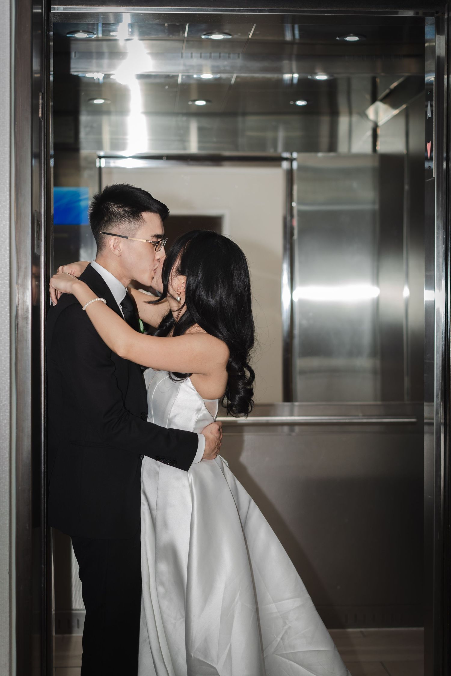 Bride and groom sharing a romantic embrace in a modern elevator during their wedding celebration at Sheraton Parkway Toronto North in Richmo