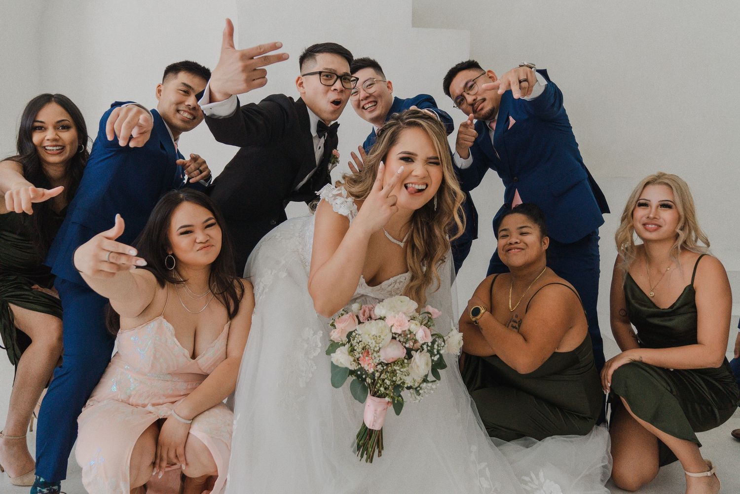 Bride and groom celebrating with their wedding party in a playful group portrait filled with laughter and expressive poses.