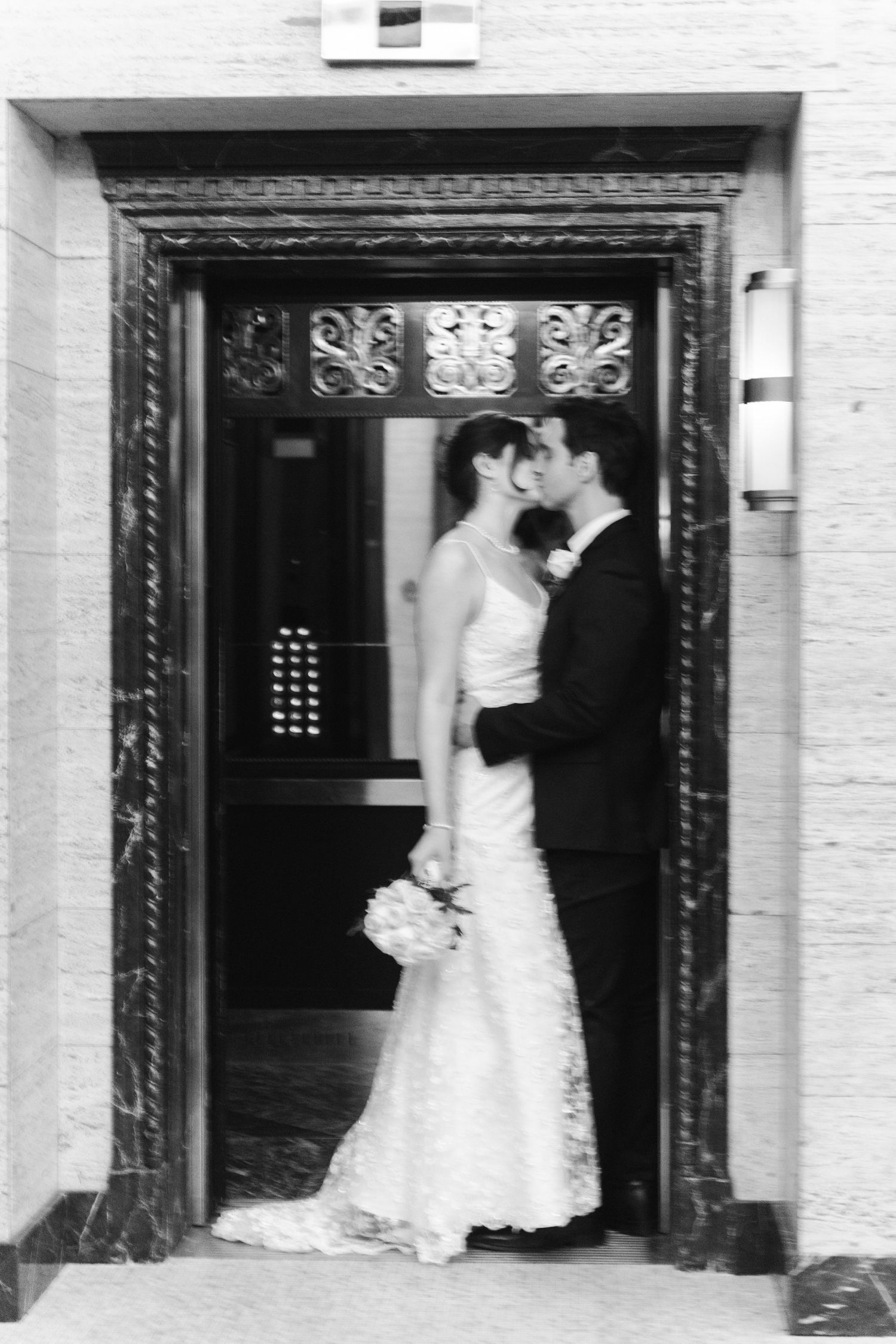 Black-and-white wedding portrait of a bride and groom embracing in the doorway of an ornate building at the Royal York hotel