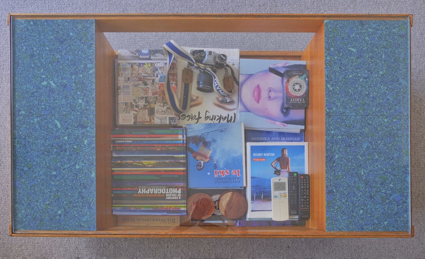 Wooden cabinet with blue speckled side panels holding a collection of CDs and music albums on display.