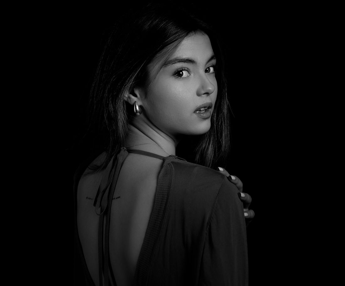 Elegant black and white photo of a young woman in a backless dress glancing back over her shoulder.