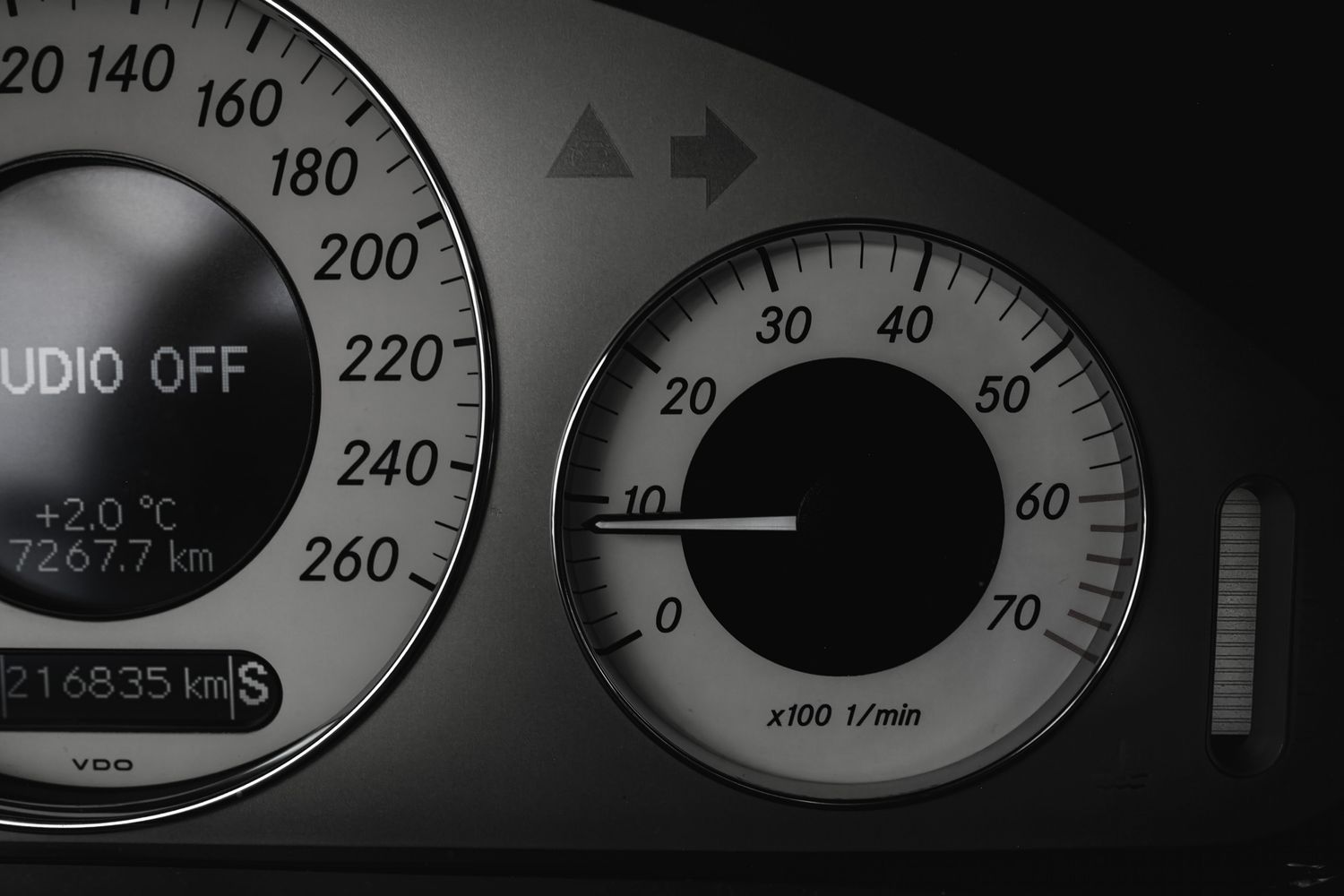 Close-up black and white car dashboard showing speedometer and RPM gauge with VDO display.