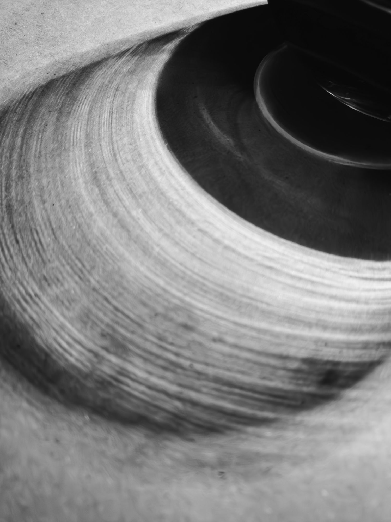 Abstract black and white macro photo of a wine glass shadow on a table showing circular grooves.