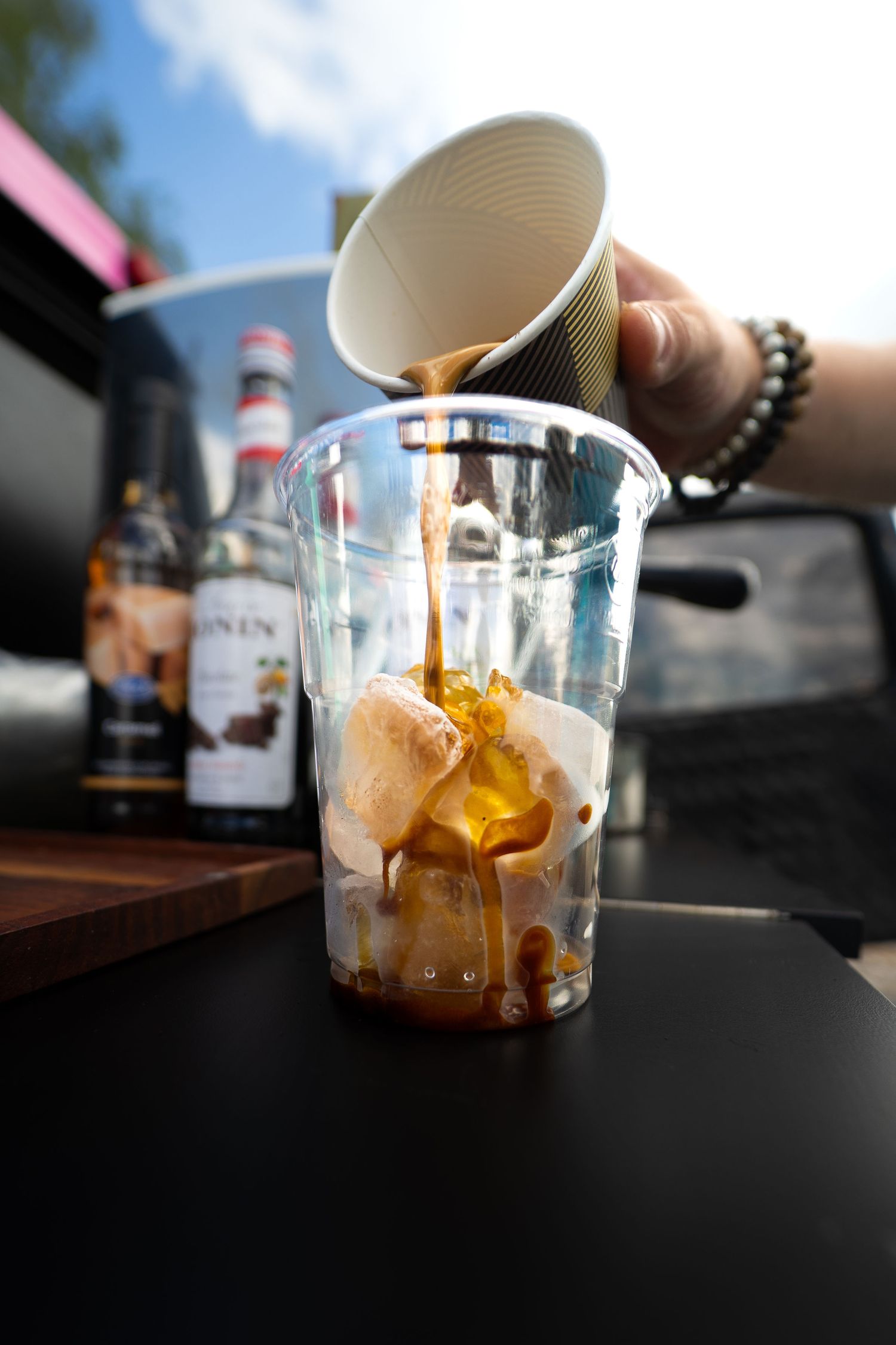 Hot espresso being poured over ice cream scoops in a plastic cup to make an affogato coffee dessert photoshoot in Lappeenranta.