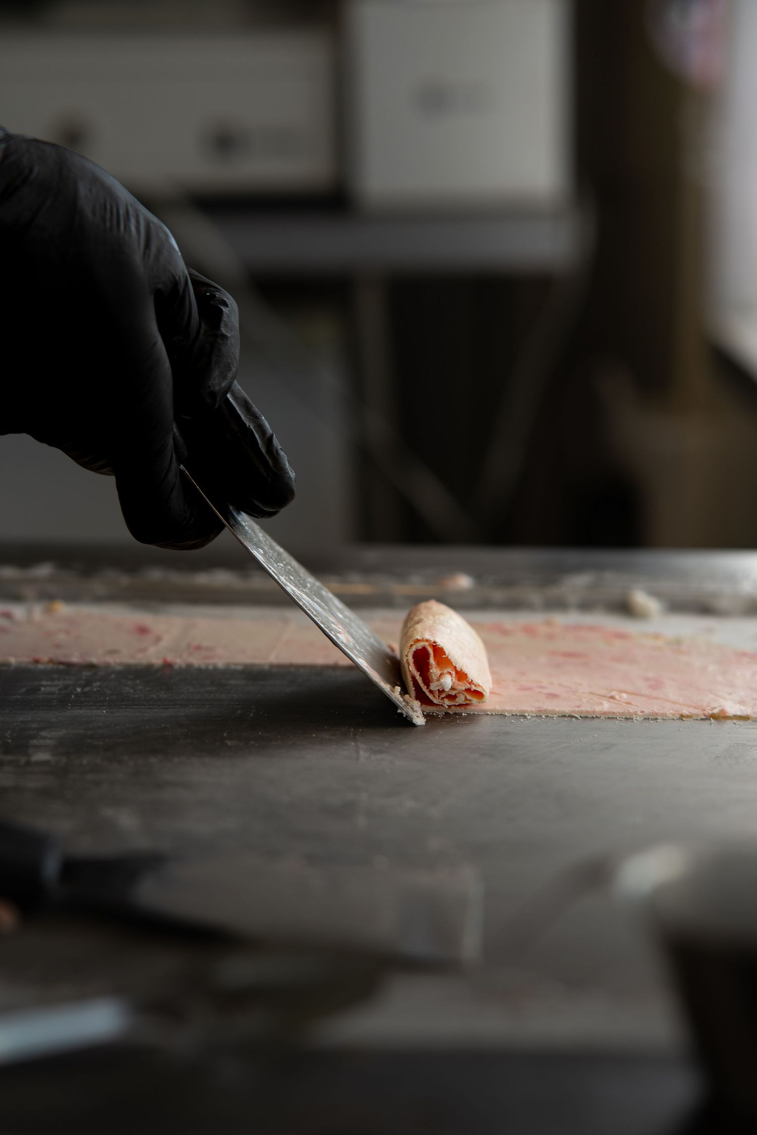 Chef in black gloves preparing roll icecream.
