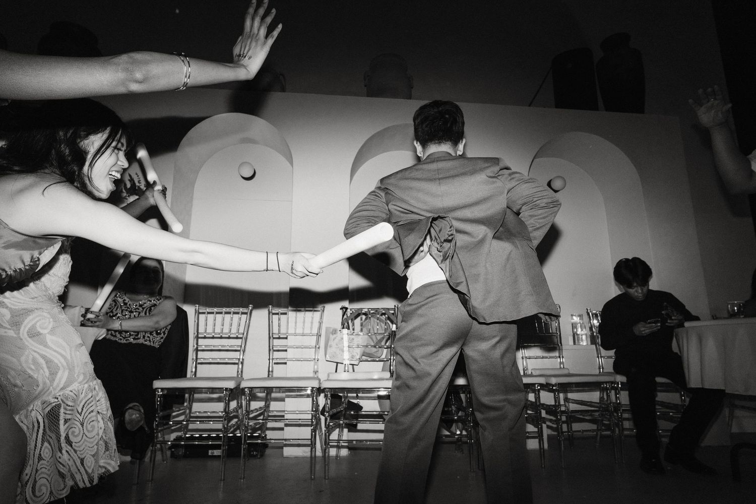 Black and white wedding reception dance floor photo with guests dancing energetically at night.