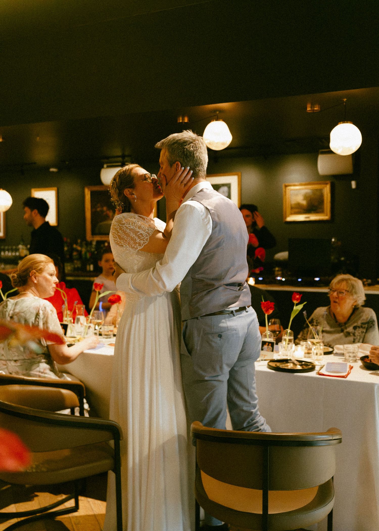 Bride and groom sharing first dance kiss at intimate wedding reception dinner.