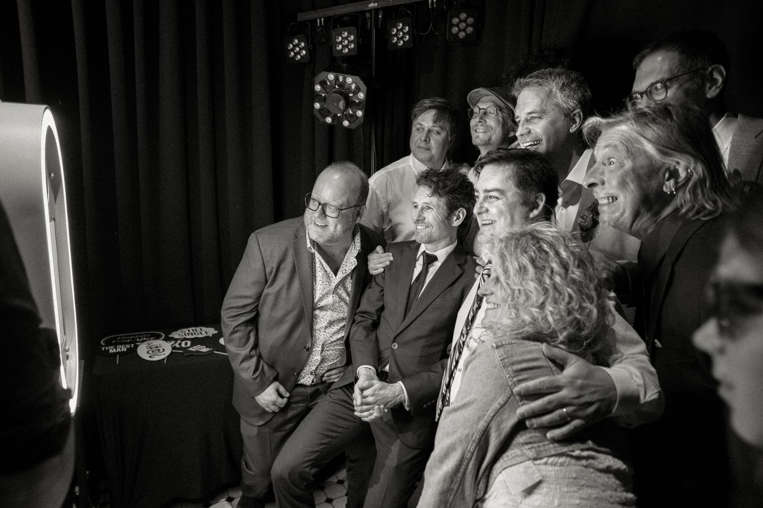 Group of wedding guests laughing together at photo booth in black and white.