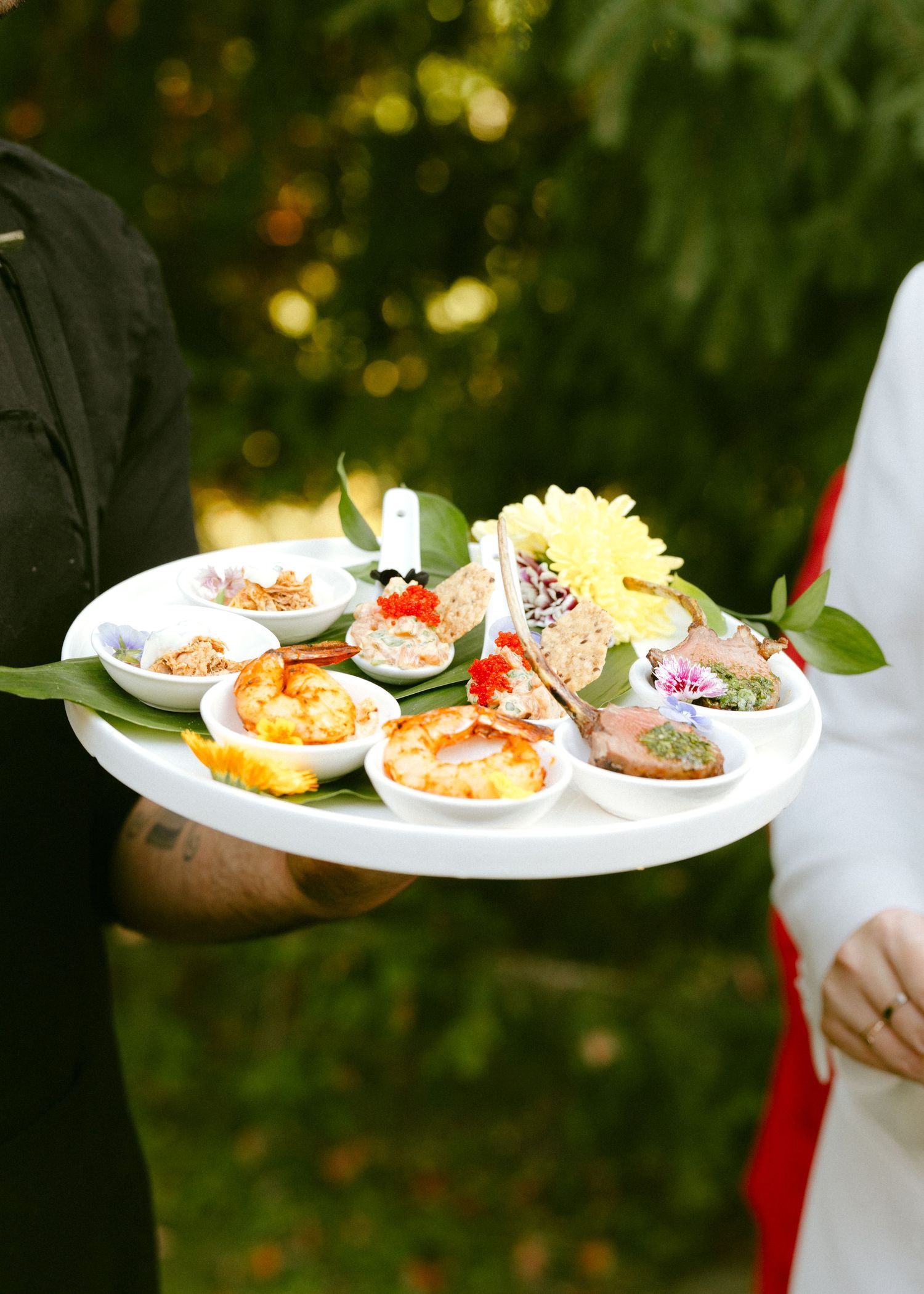 Elegant wedding appetizer tray with assorted bite-sized hors d\u0027oeuvres garnished with fresh flowers.