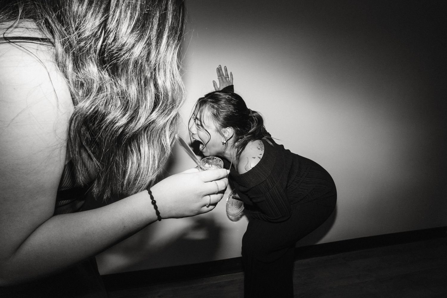 Black and white artistic photo of a child kissing a large portrait image on a gallery wall.