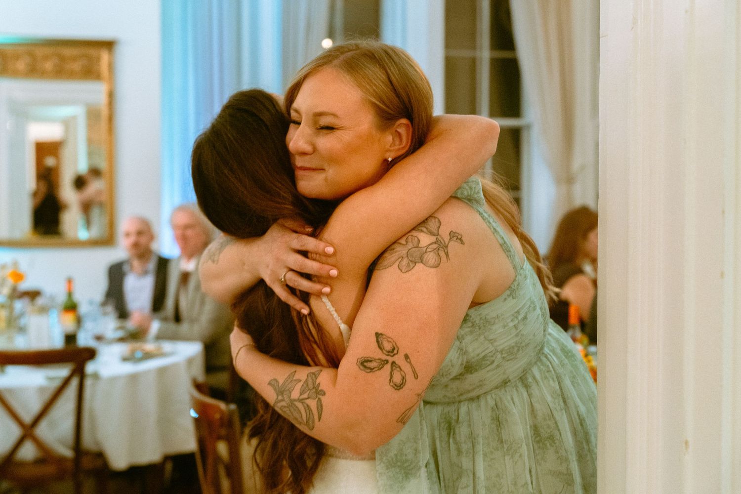 Two women sharing a warm emotional hug at a wedding reception celebration.