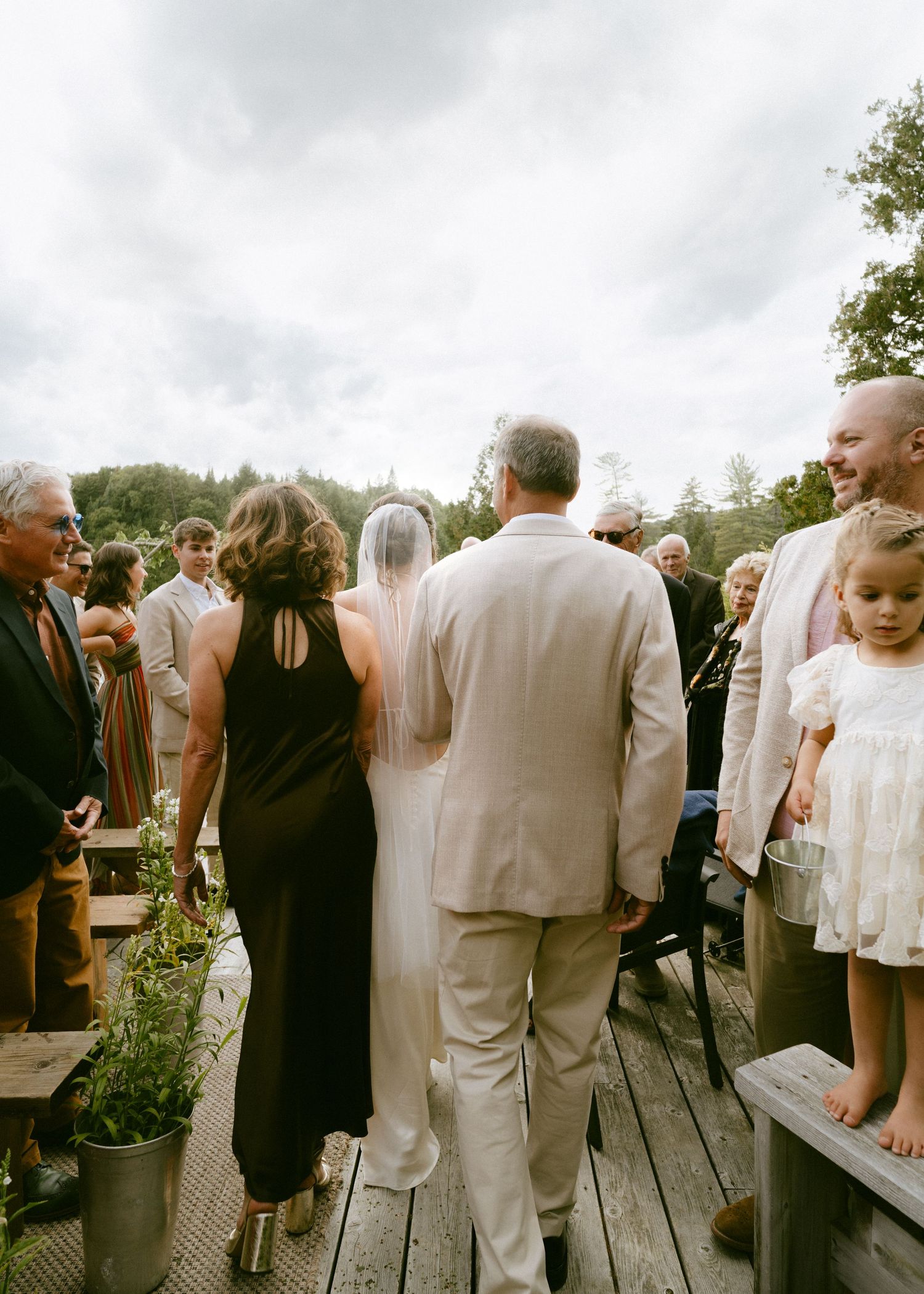 Bride walking down the aisle with her father at an outdoor wedding ceremony on a deck.