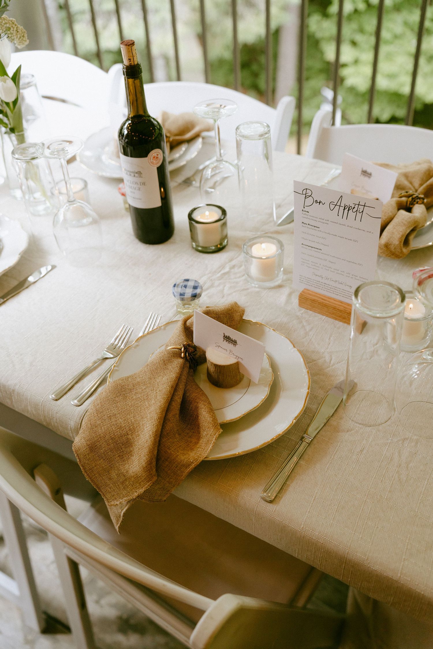Elegant wedding table setting with burlap napkin, candles, wine bottle and Bon Appetit menu card.