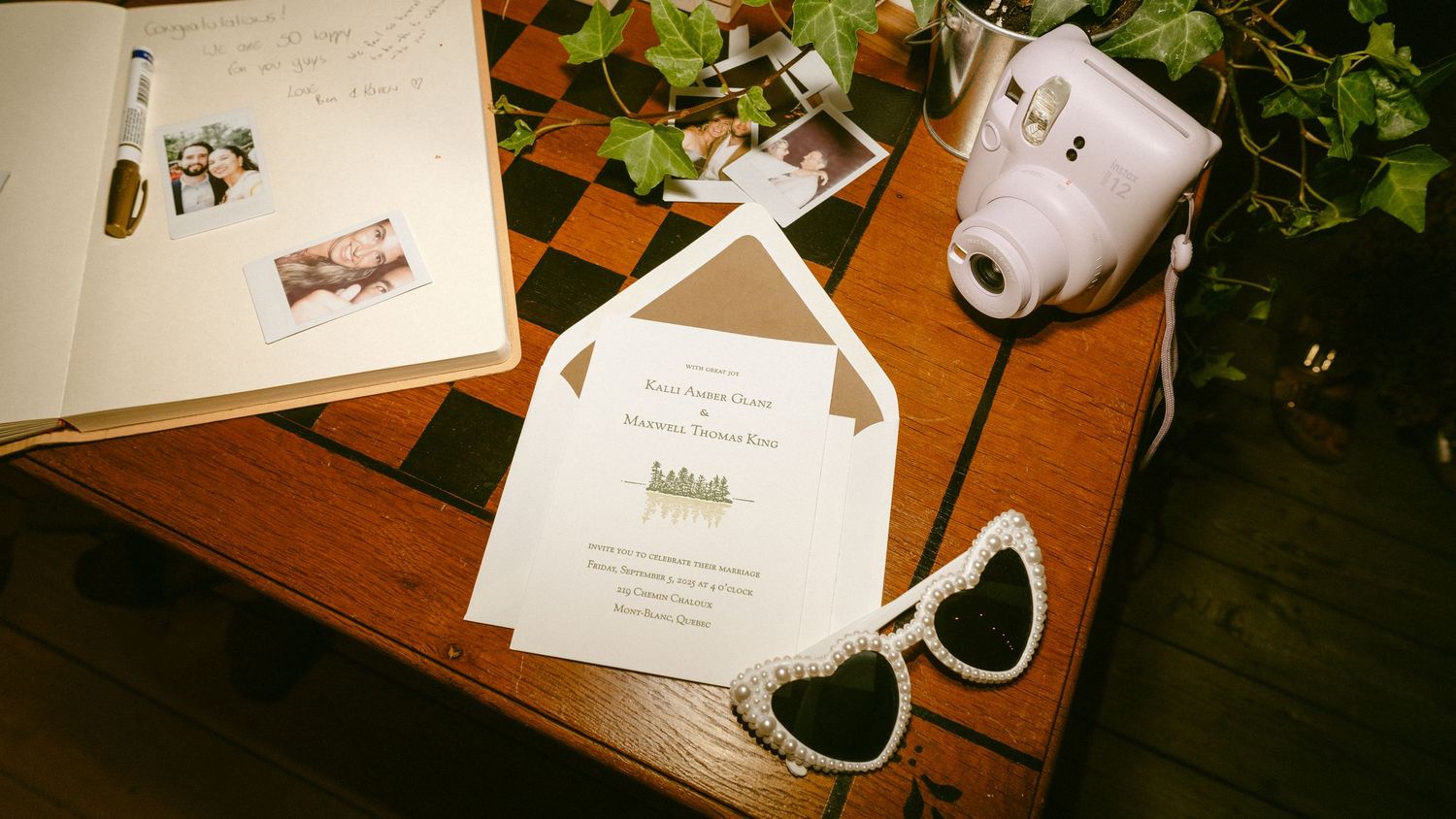 Wedding invitation, Instax camera, heart sunglasses and photos on wooden chess table.