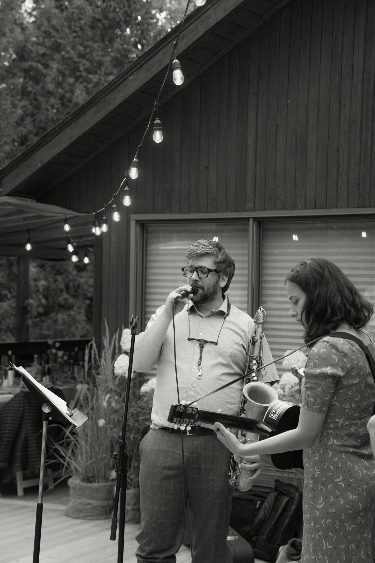 Black and white photo of a singer and a saxophonist at outdoor wedding.