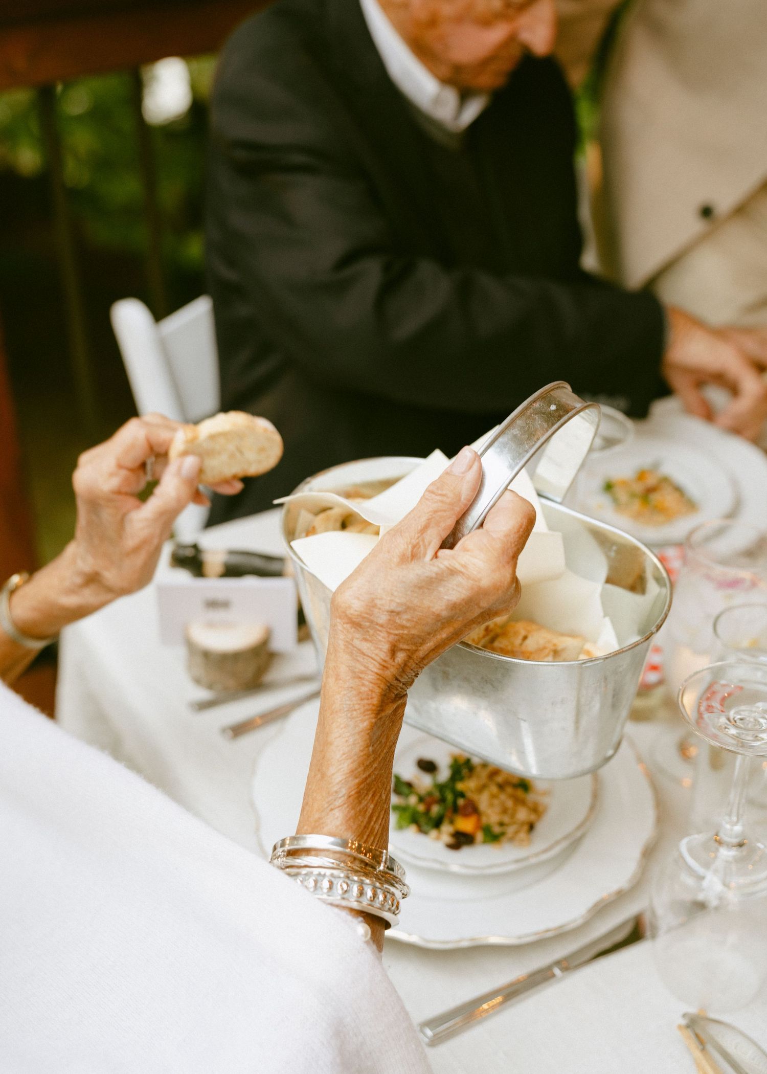 Elderly guests dining at wedding reception table with silver ice bucket and gourmet food.