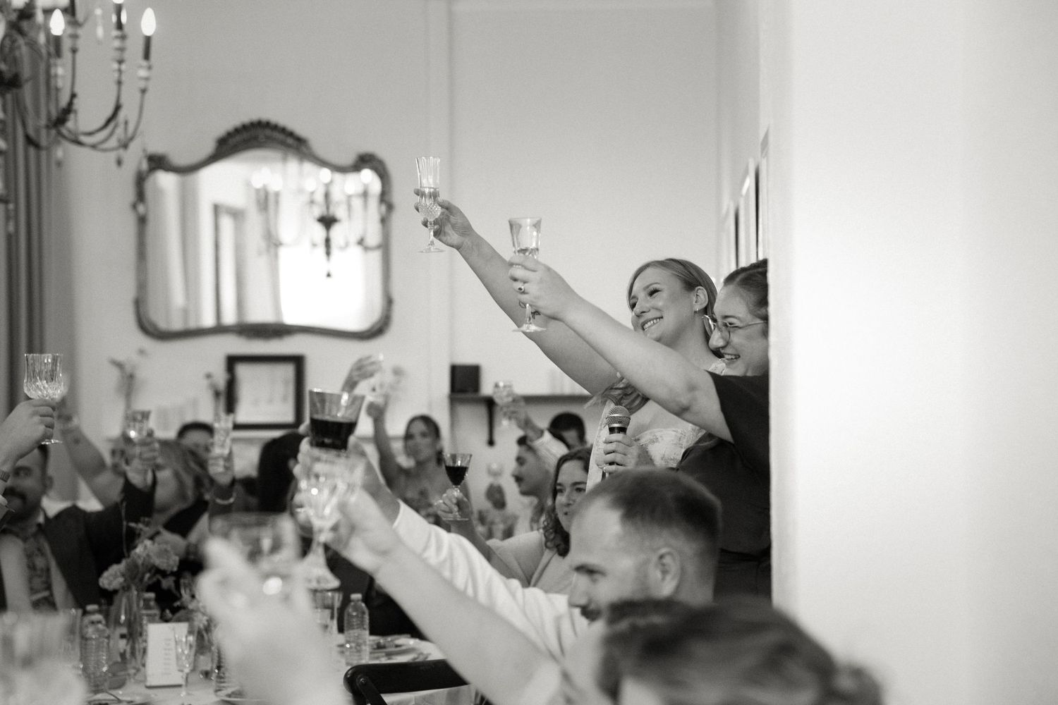 Wedding guests raising champagne glasses in a joyful toast at a reception.