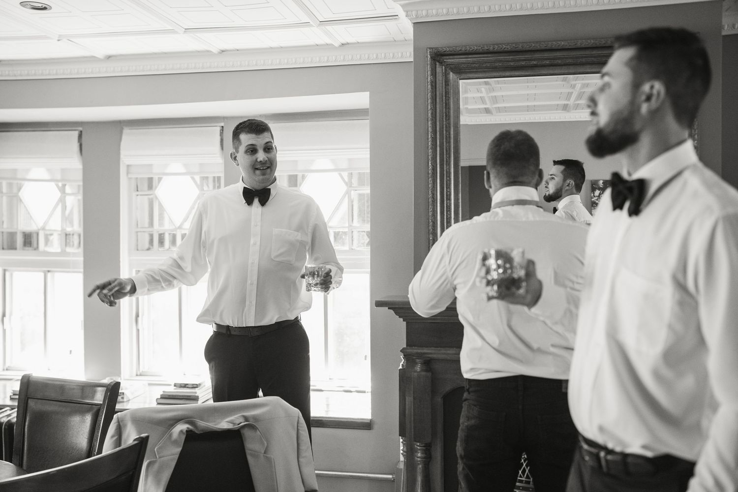 Groomsmen in white shirts and bow ties celebrating with drinks before the wedding ceremony.