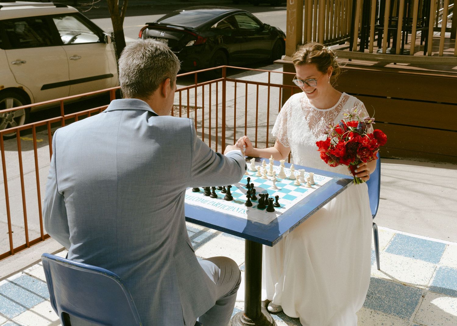 Bride and groom playfully enjoy a chess game outdoors on their wedding day.