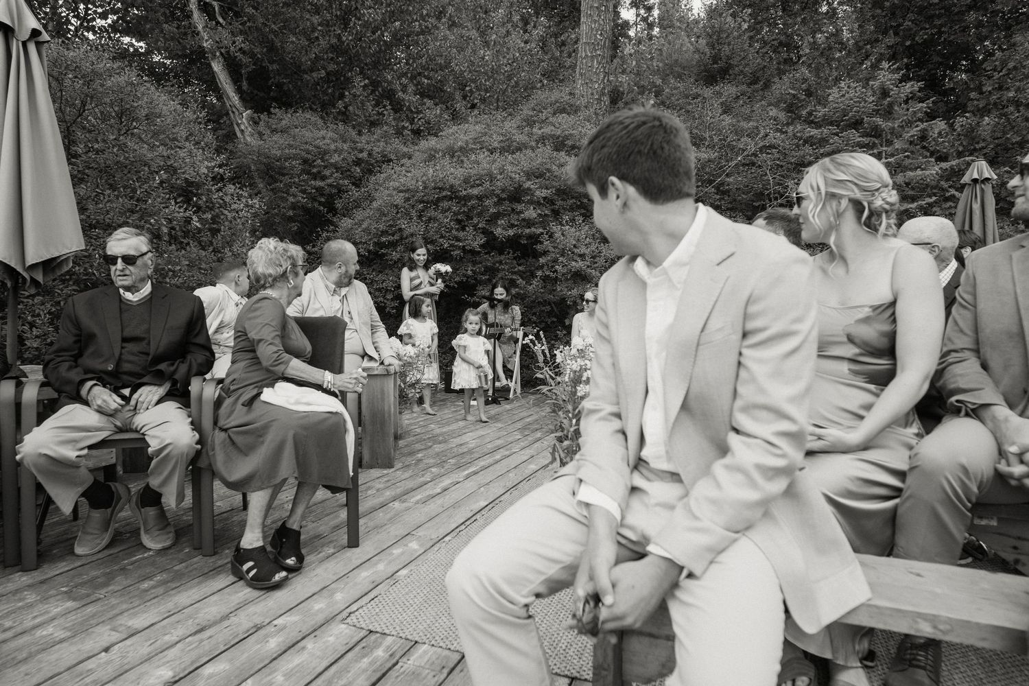 Black and white photo of wedding guests seated outdoors during a garden ceremony.