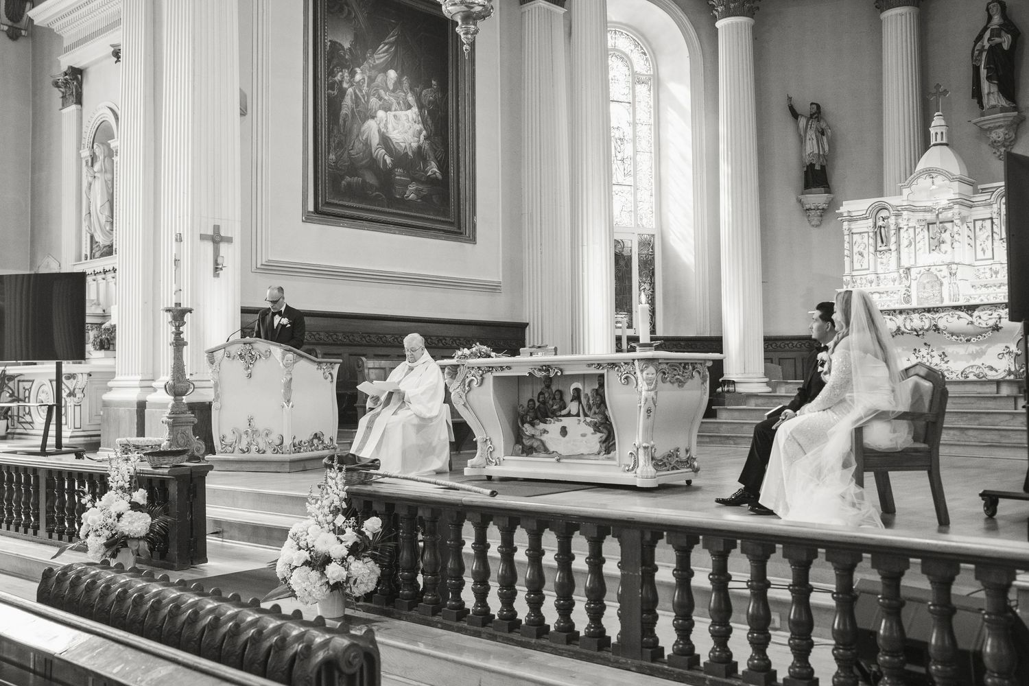 Black and white photo of bride and groom seated at the altar during a traditional church wedding ceremony.