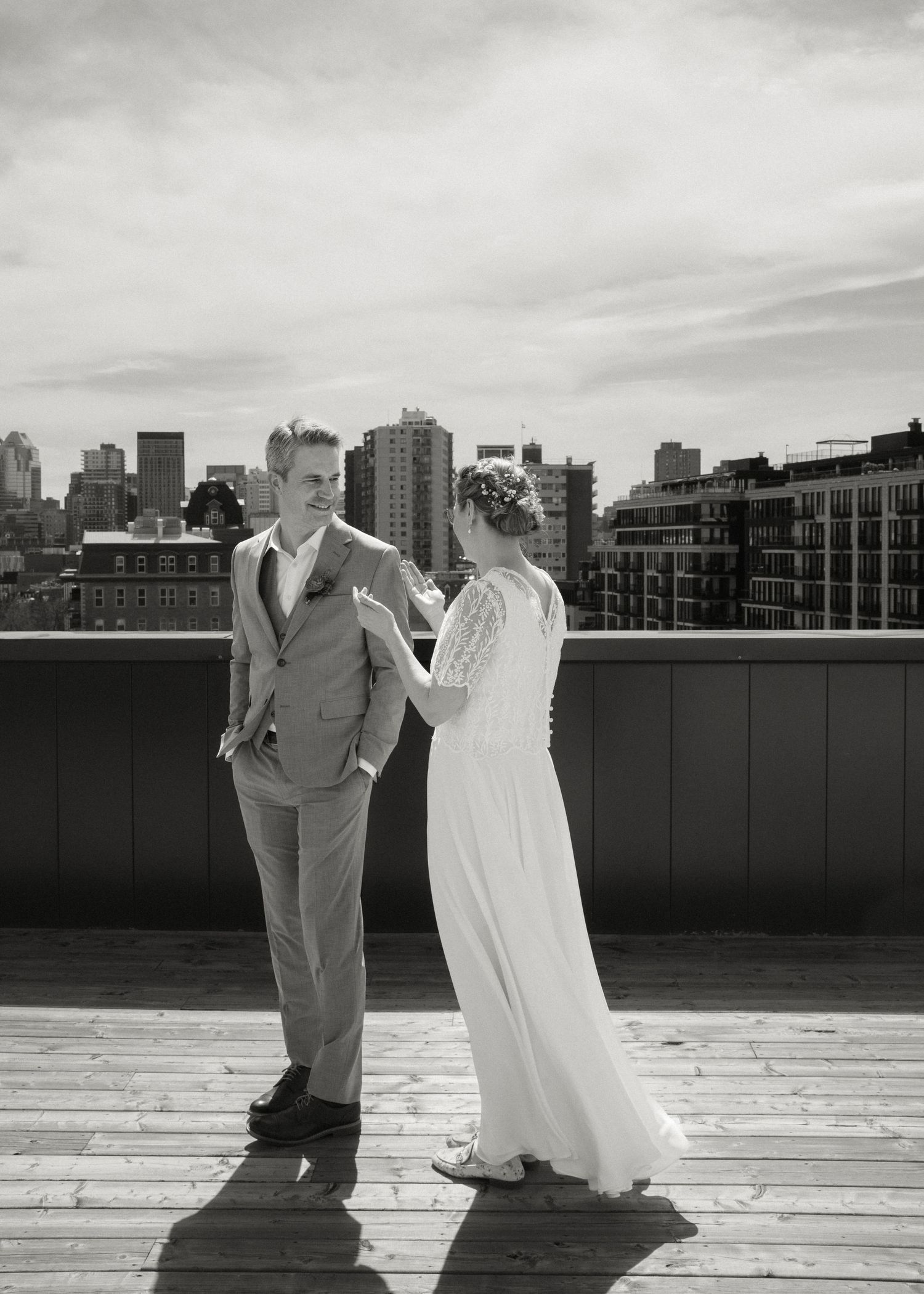 Black and white photo of bride touching grooms face during first look on urban rooftop.