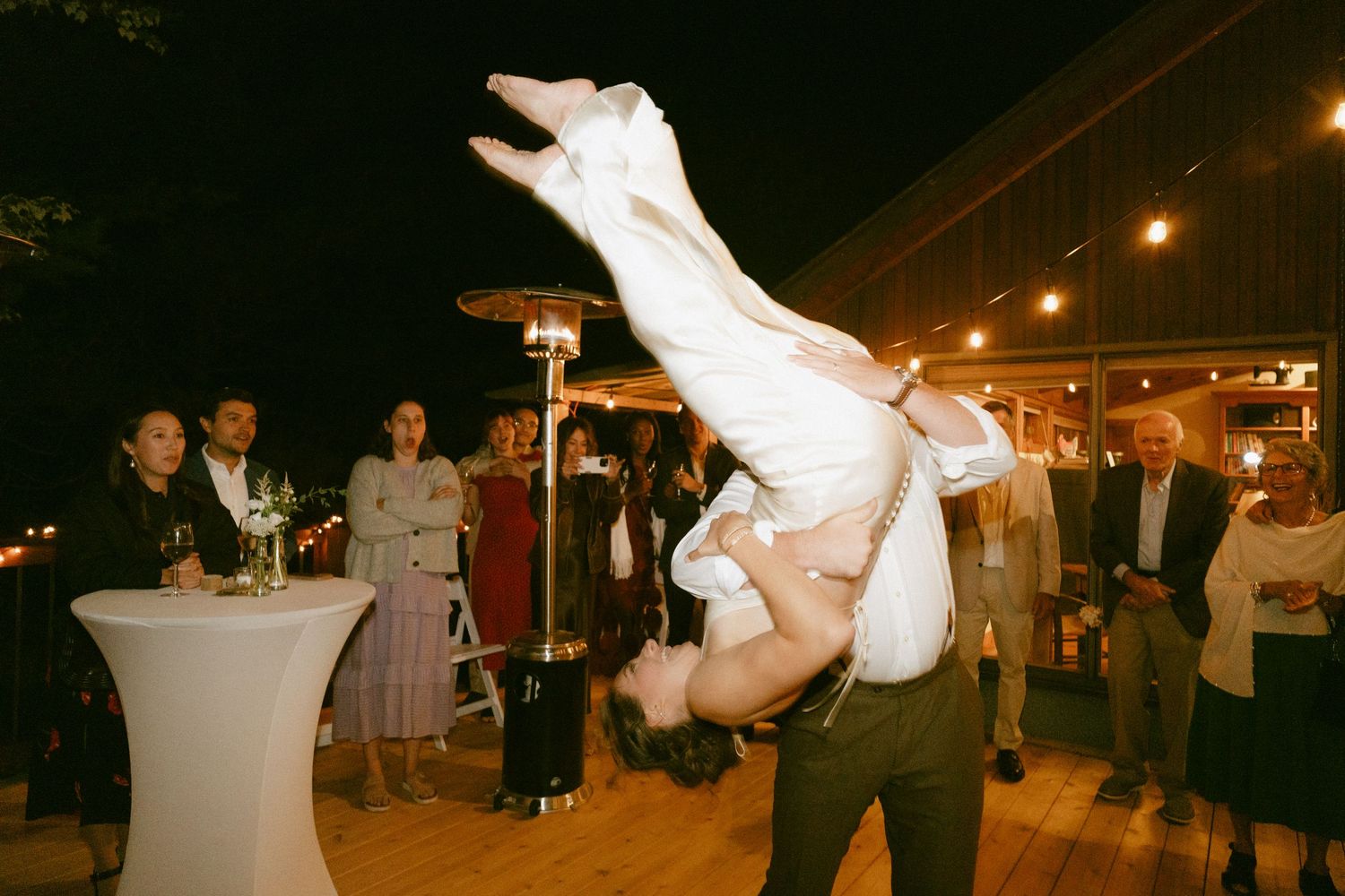 Groom lifting bride high in the air during energetic wedding reception dance performance.