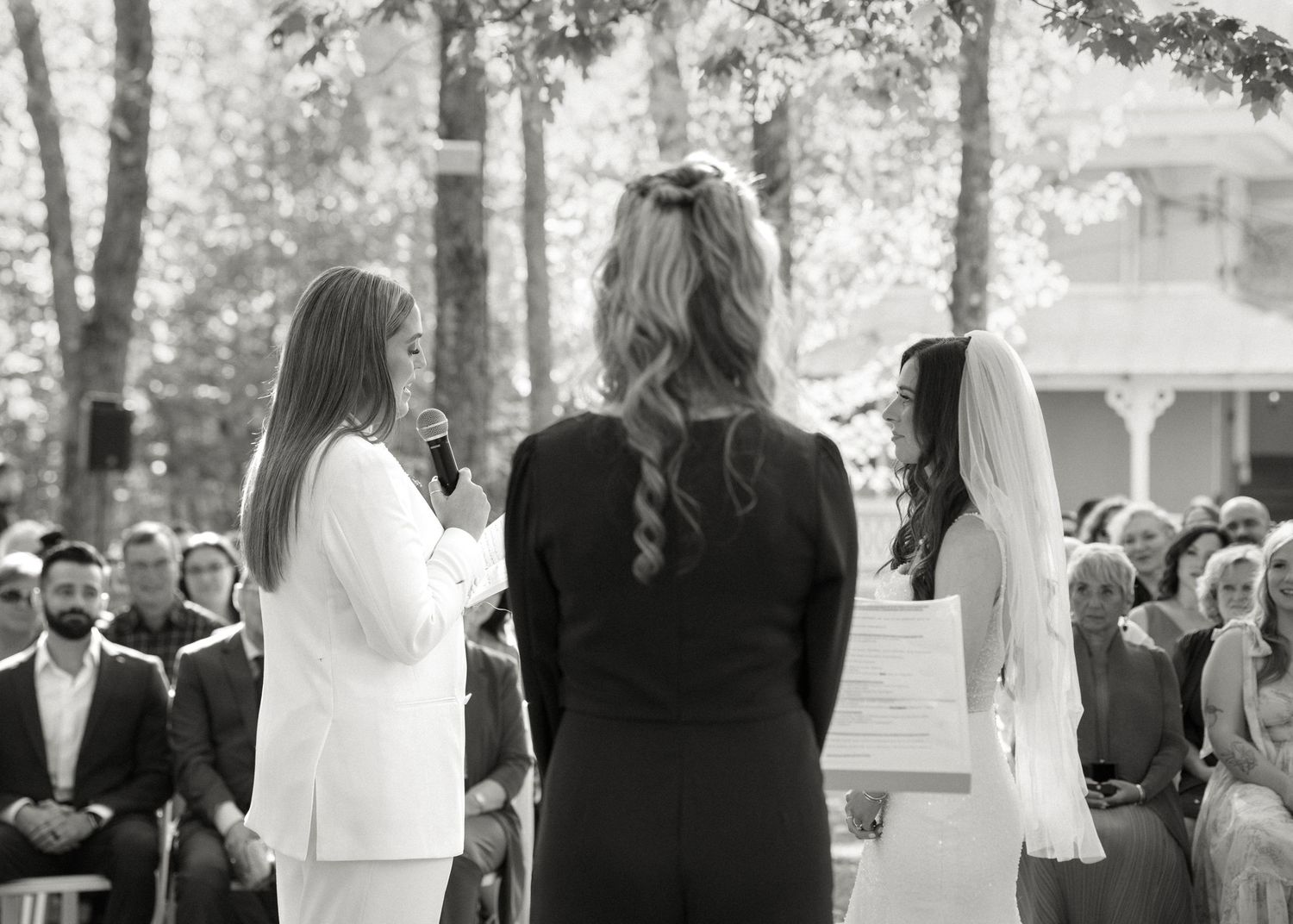 Officiant reads vows as bride and groom stand together at intimate outdoor wedding ceremony.