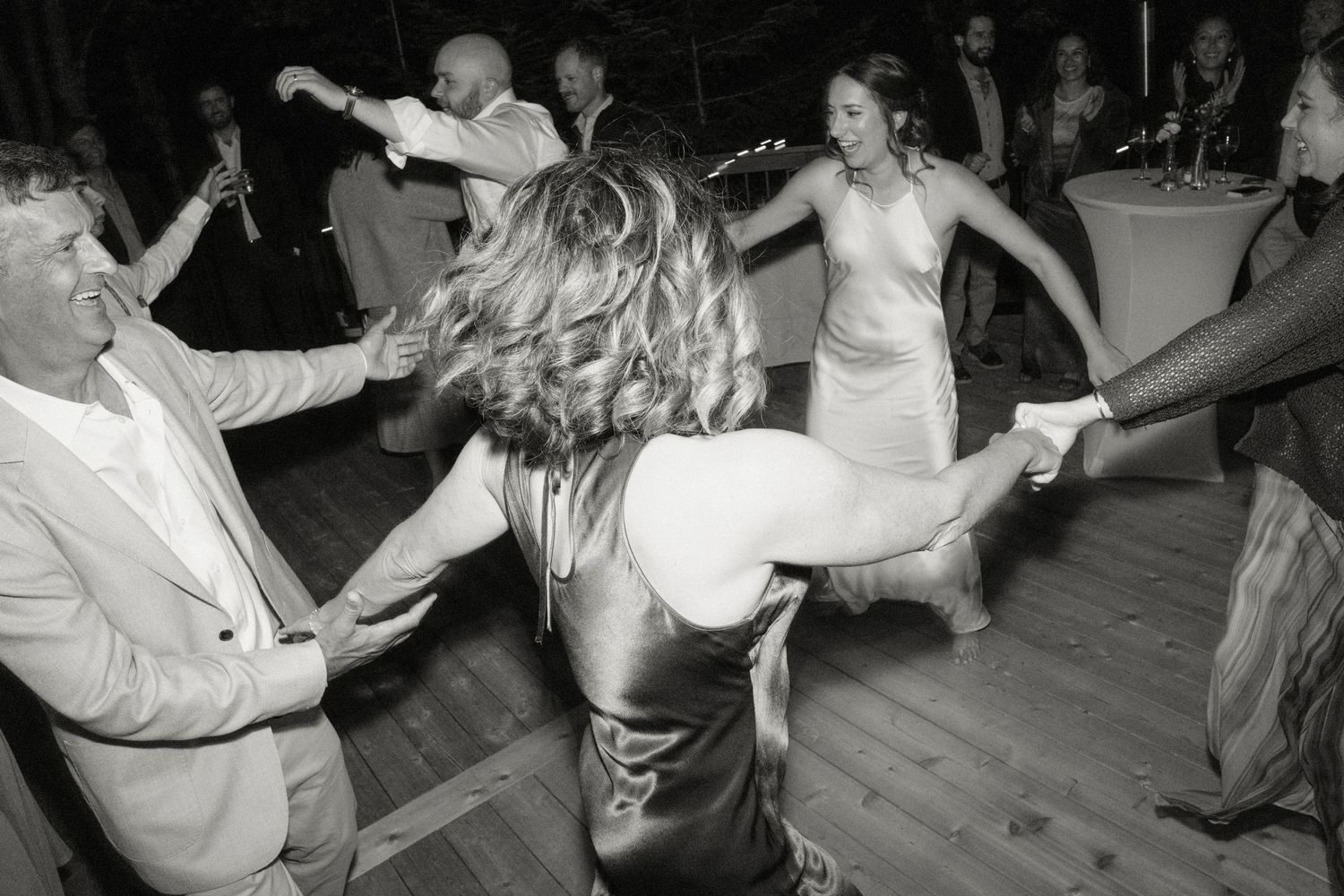 Guests dancing energetically at a wedding reception in black and white photo.