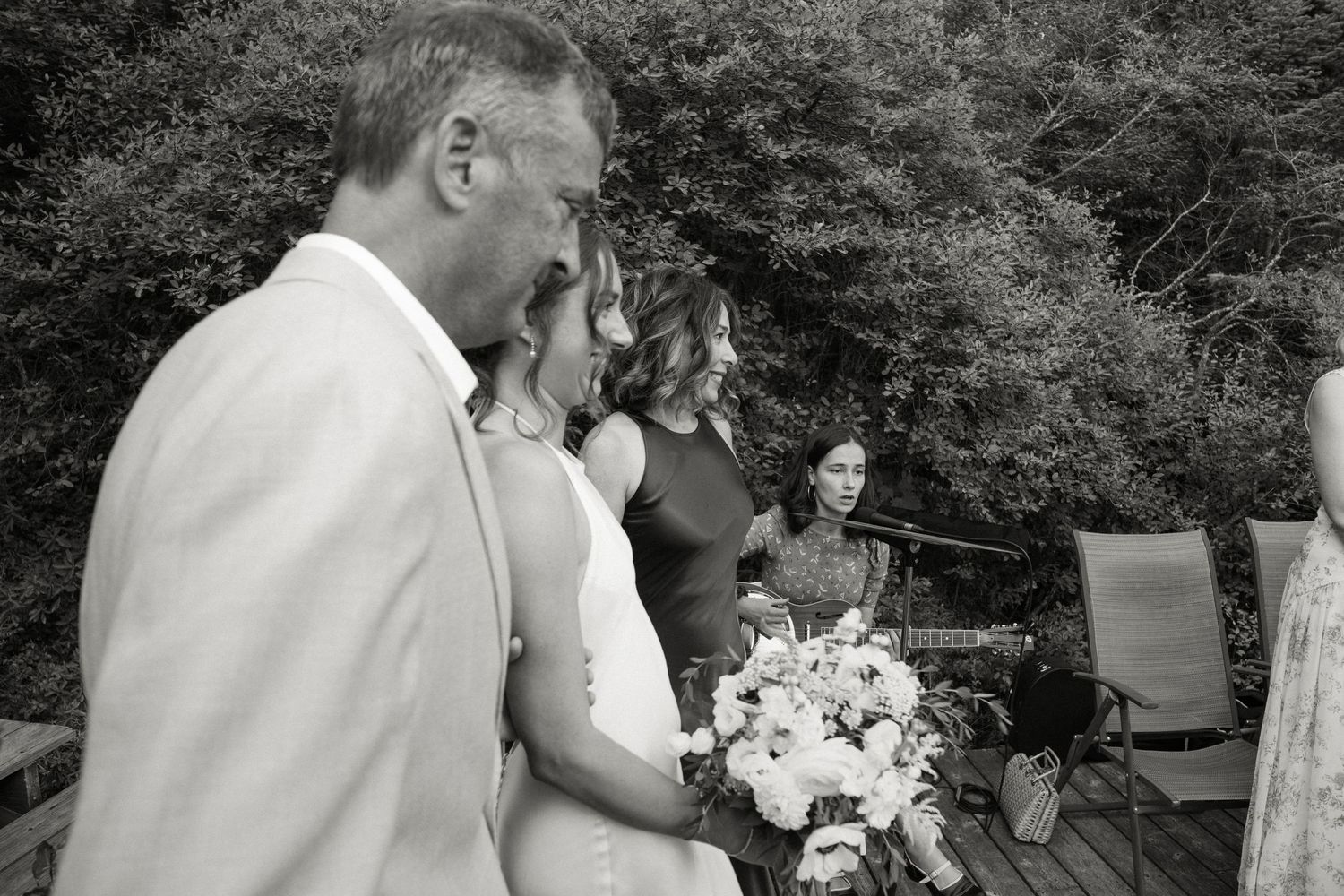 Black and white photo of bride with father and guests during outdoor wedding processional.