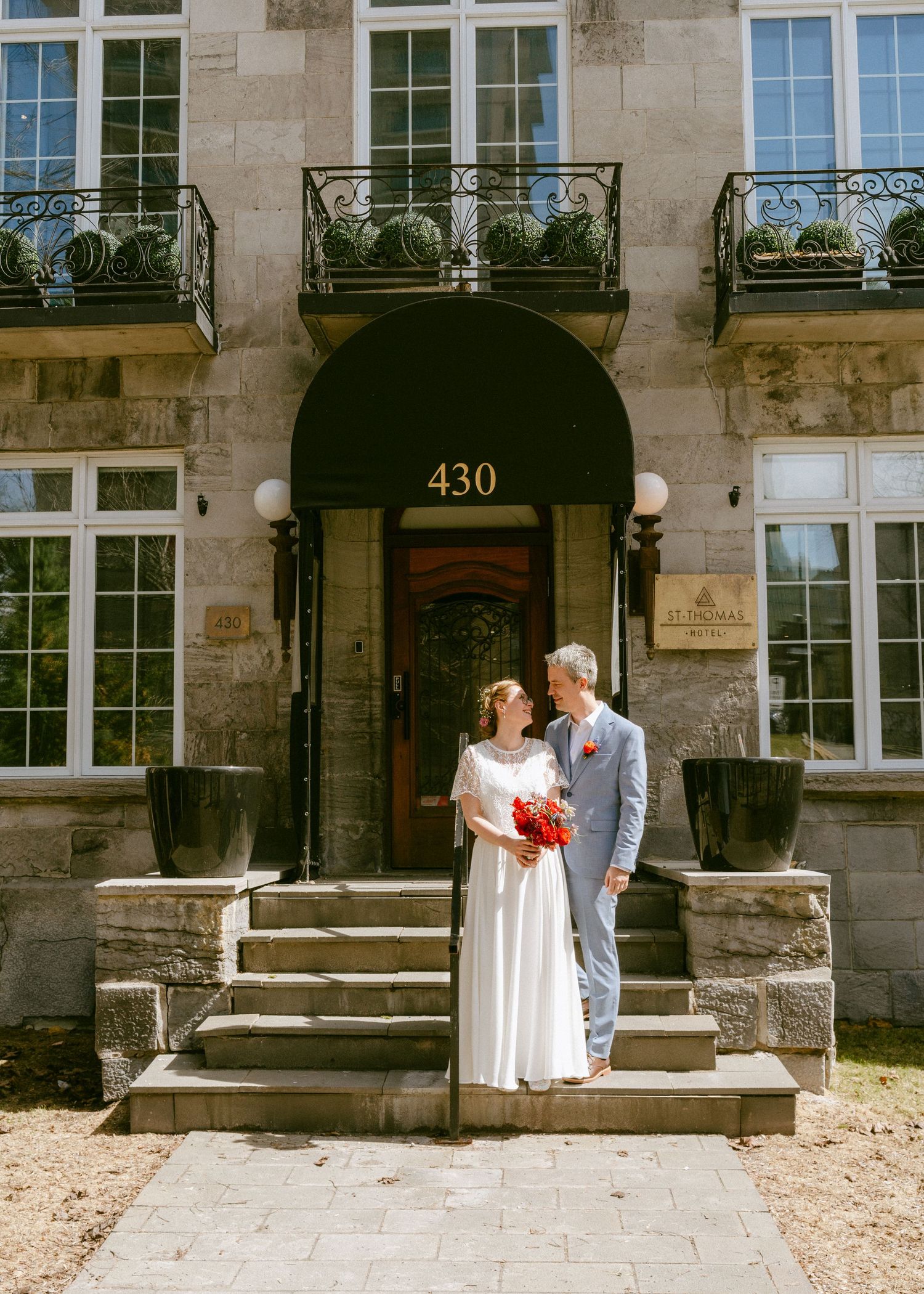 Elegant couple poses on steps of historic stone building 430 on their wedding day.