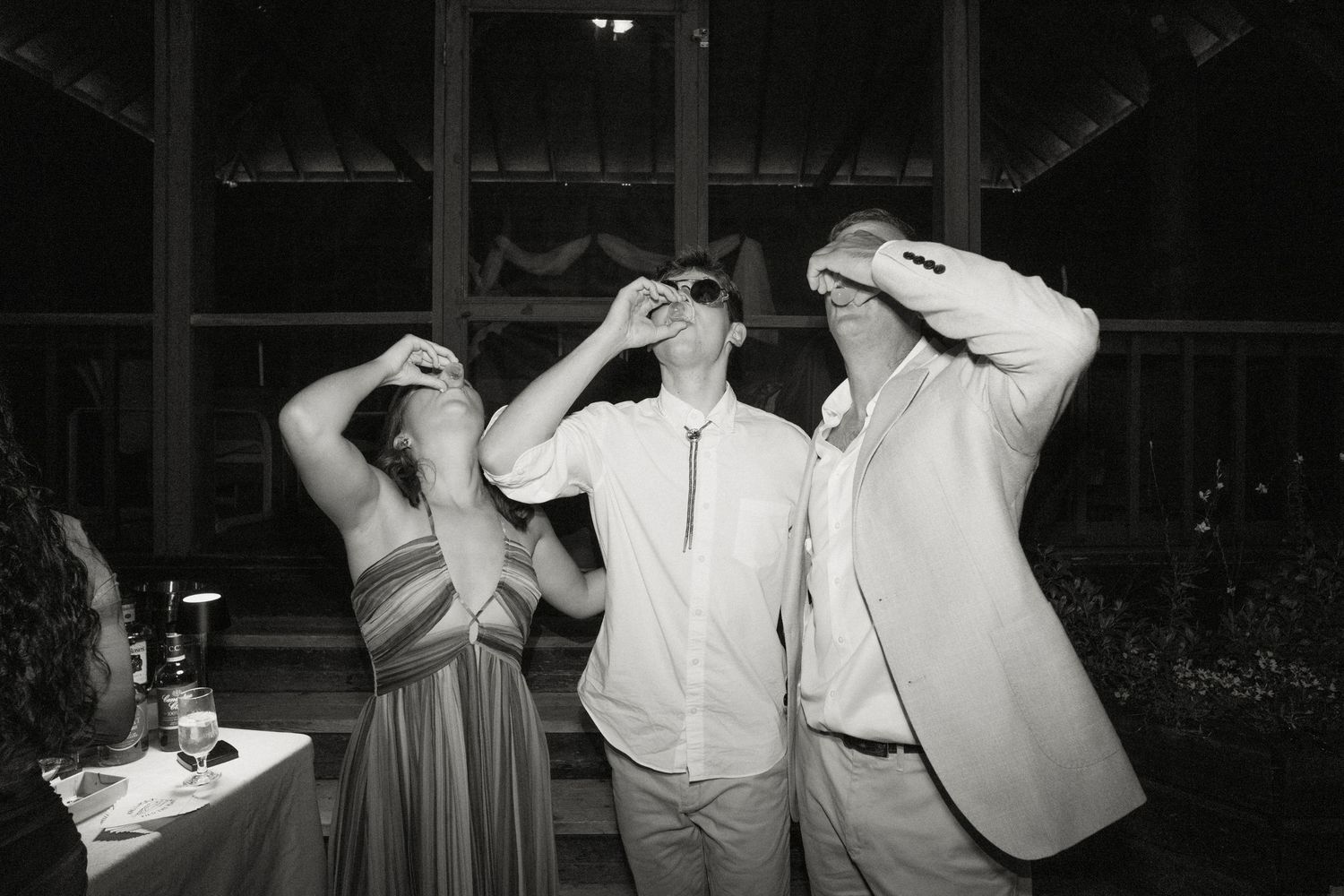 Three wedding guests playfully posing with hands on heads in black and white.