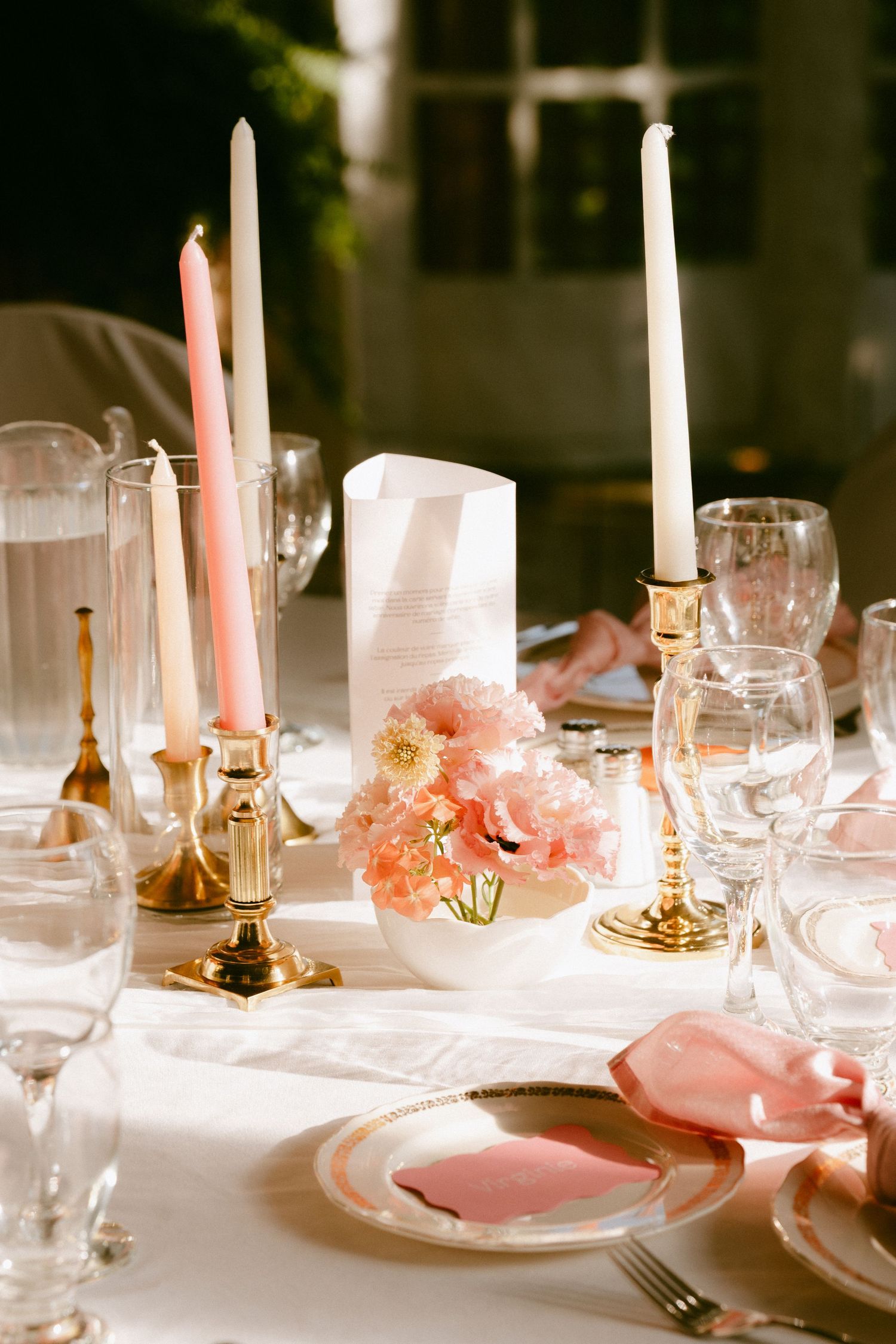 Elegant wedding table setting with gold candlesticks, pink tapers, blush florals, and crystal glassware.