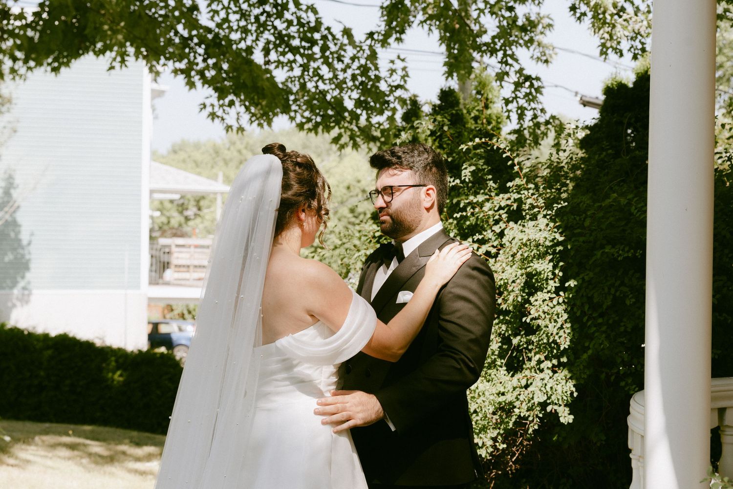 Bride and groom share an emotional first look moment outdoors under lush green trees.