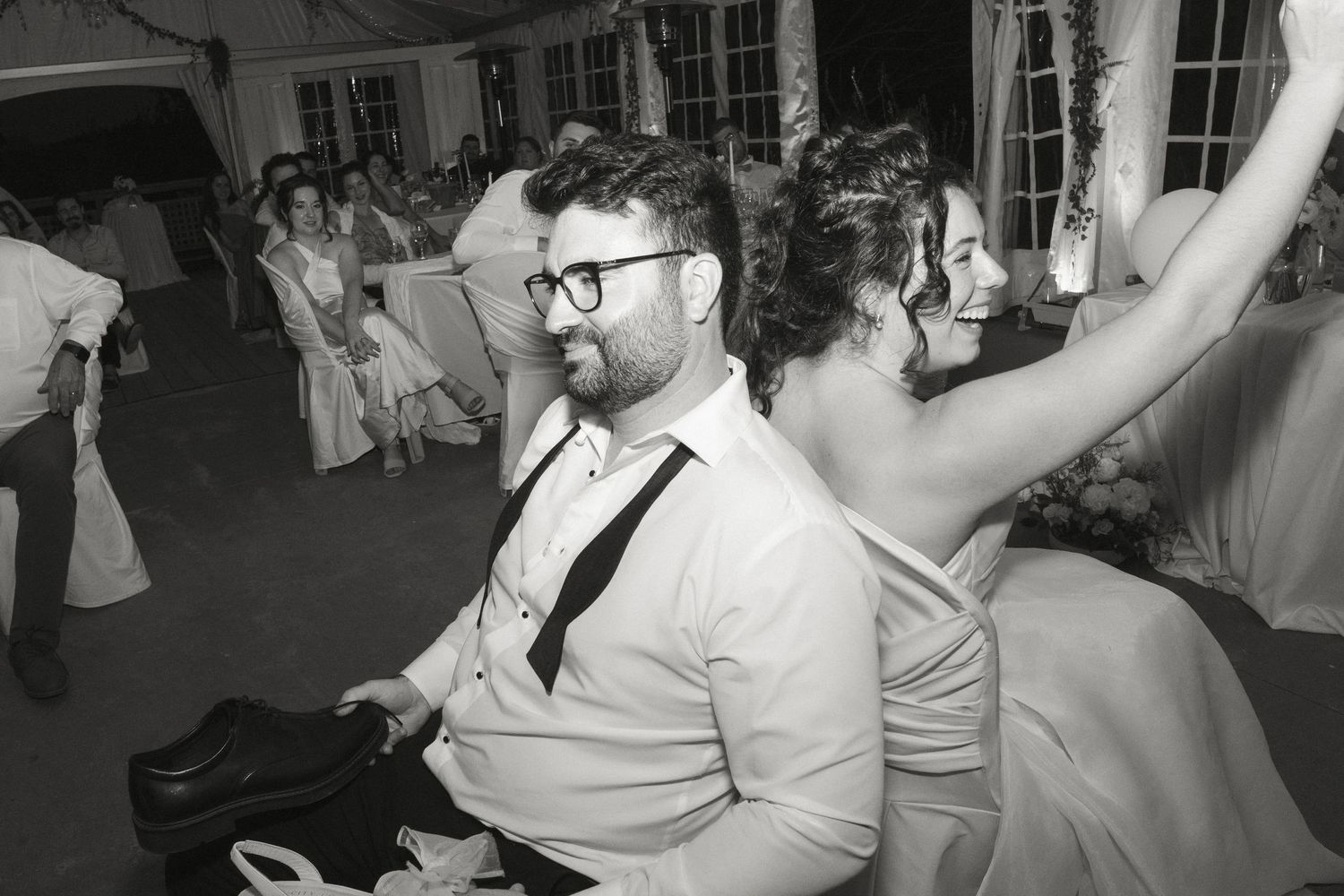 Black and white photo of groom smiling during wedding reception dance.