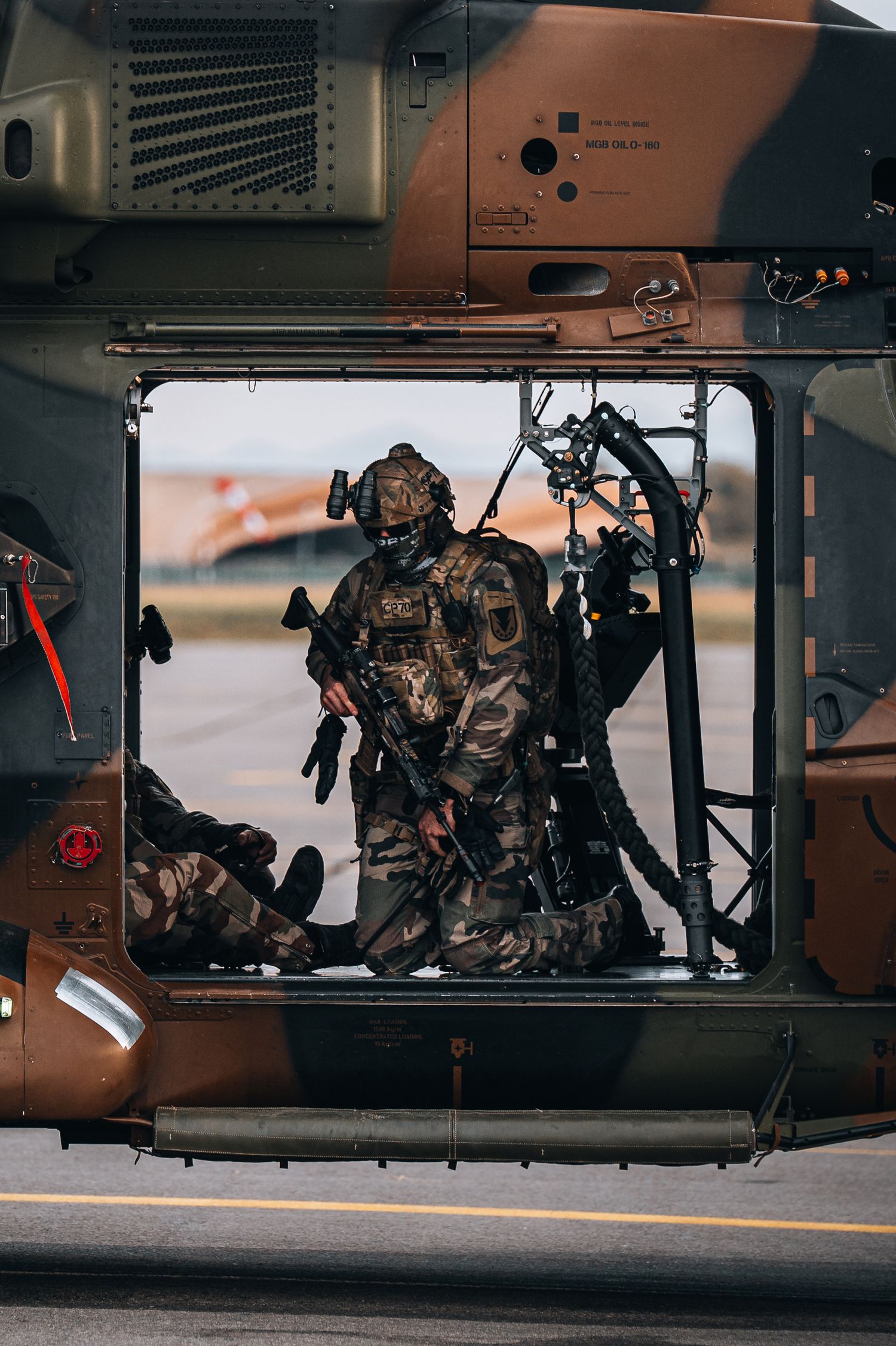 Armed soldiers in camouflage gear inside military helicopter preparing for deployment.