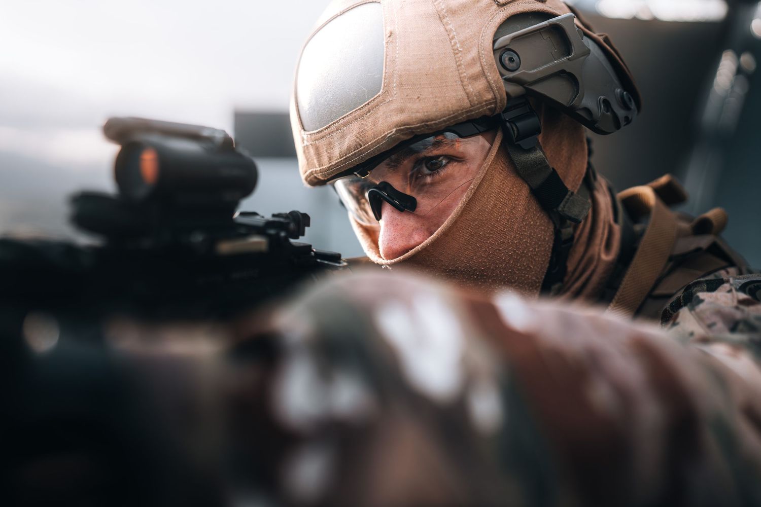 Close-up of a soldier in camouflage helmet aiming rifle with intense focus during naval operation.