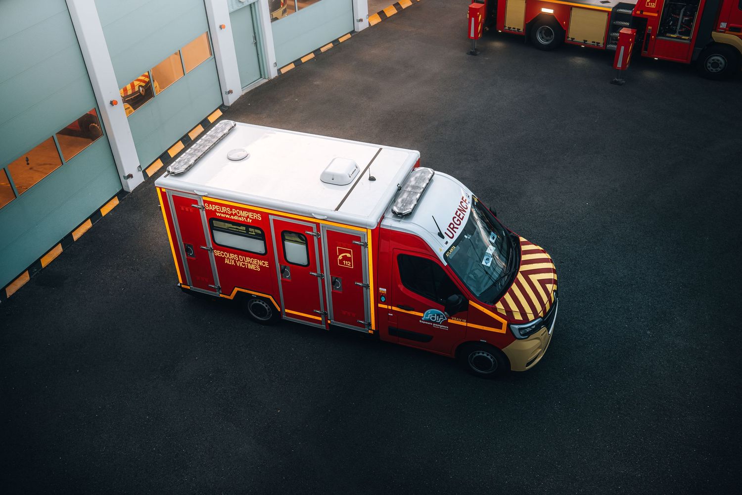 Aerial view of a red French fire department emergency ambulance vehicle inside a station.