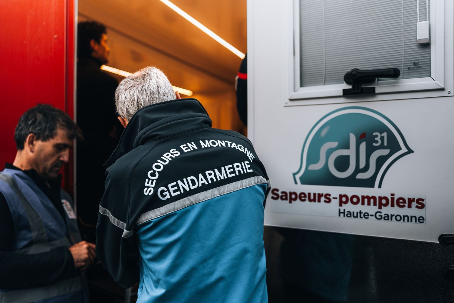 Gendarmerie mountain rescue officer and sapeurs-pompiers Haute-Garonne firefighters collaborating.