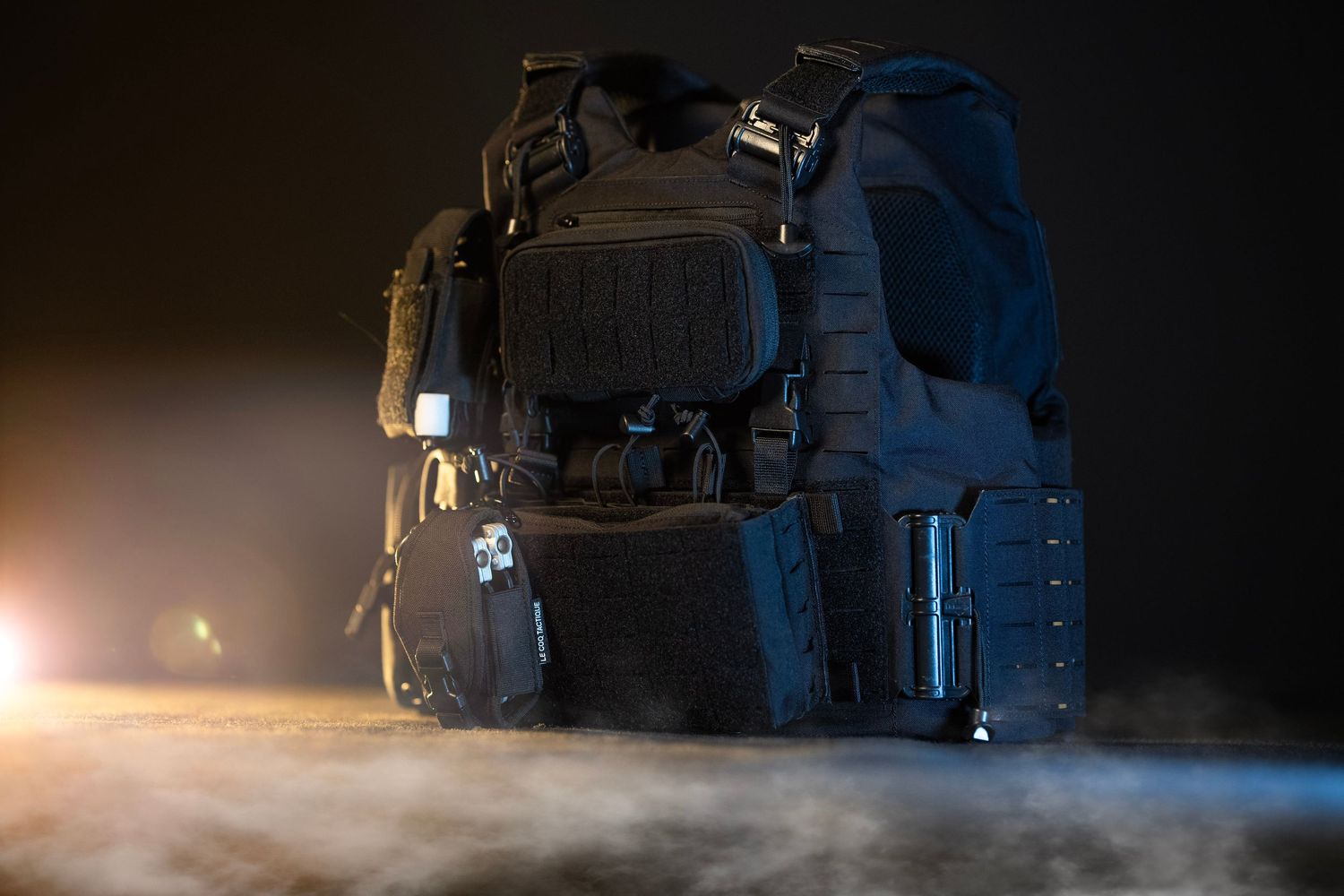 A tactical black bulletproof vest and military gear displayed dramatically with smoke and moody lighting.